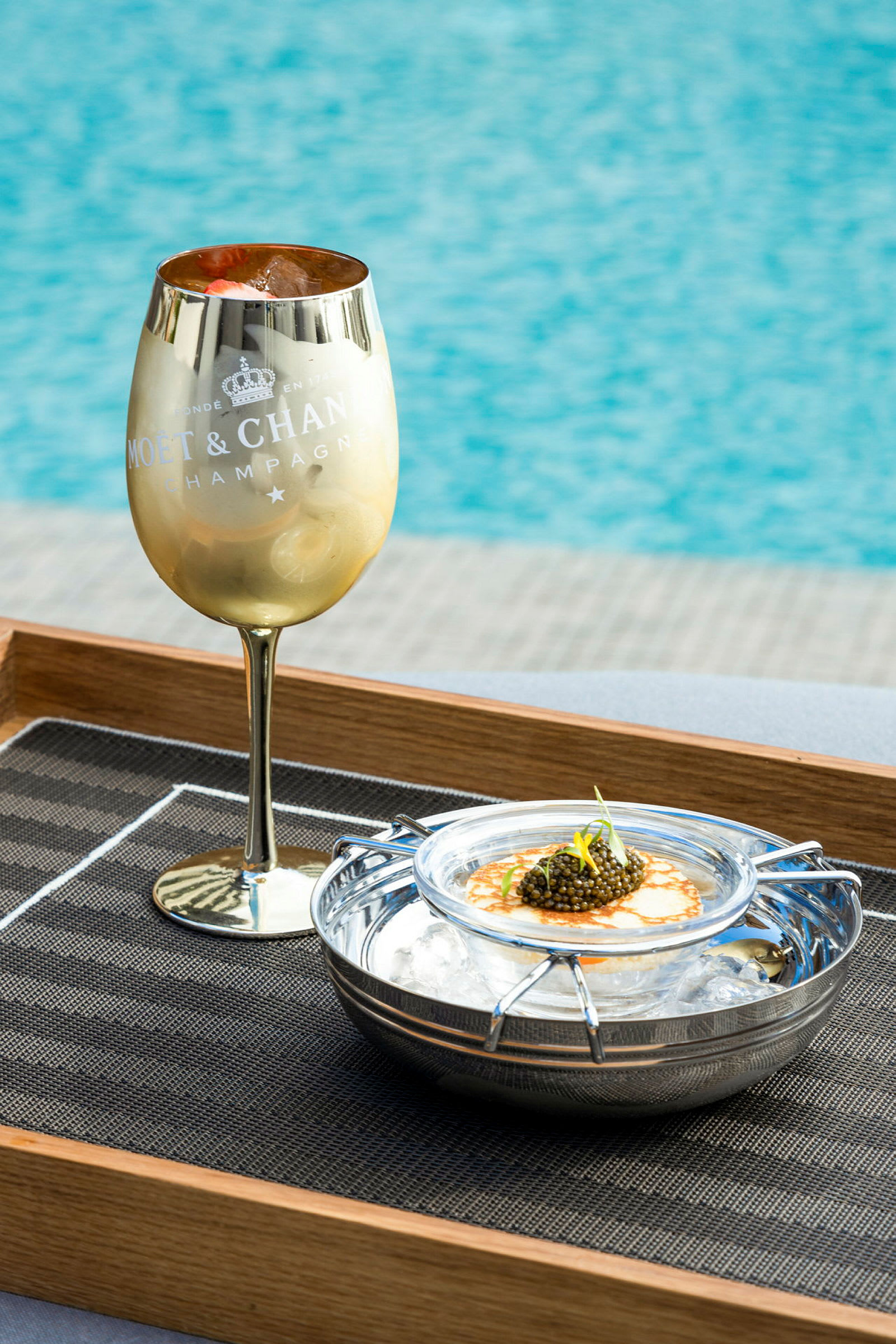 Guldfärgat champagneglas bredvid en servering av kaviar på is. (AI-genererad text)