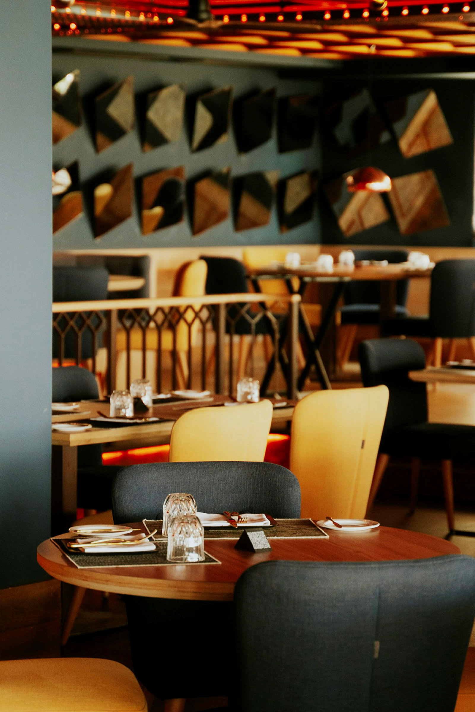 En restaurangmiljö med bord och stolar, dukade för måltider. (AI-genererad text)
