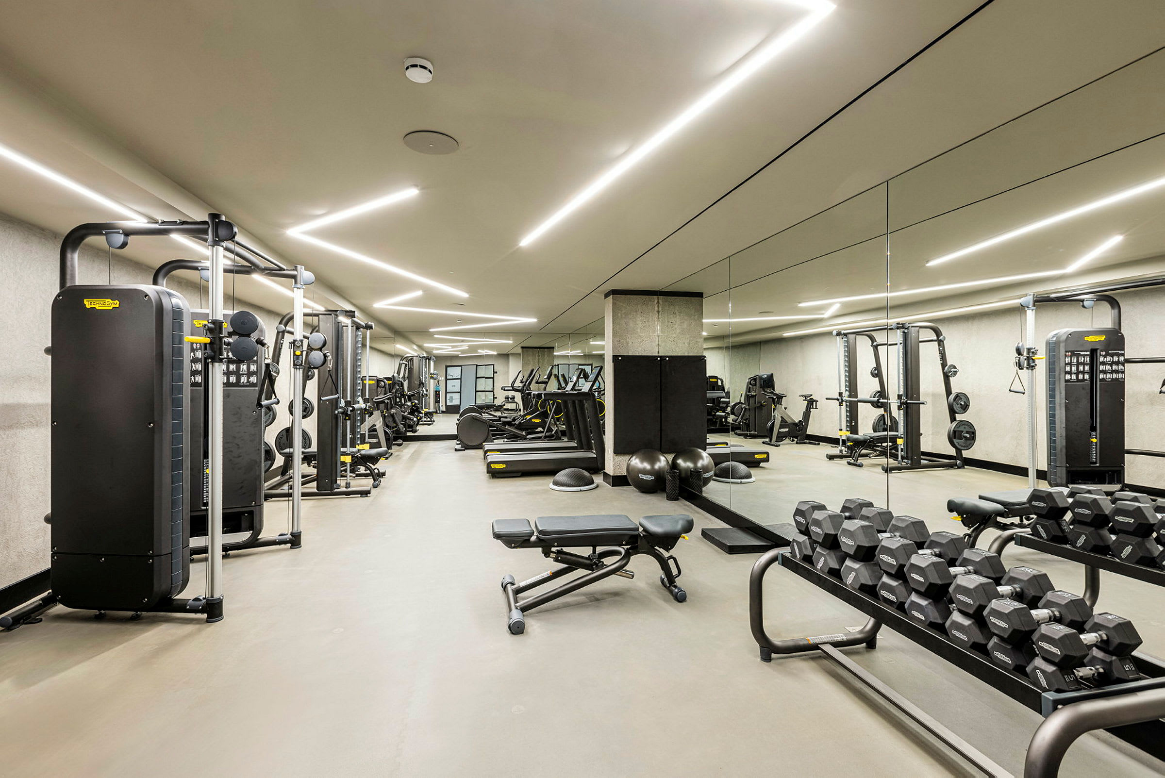 Ett gym med träningsmaskiner, hantlar och träningsbänkar. (AI-genererad text)