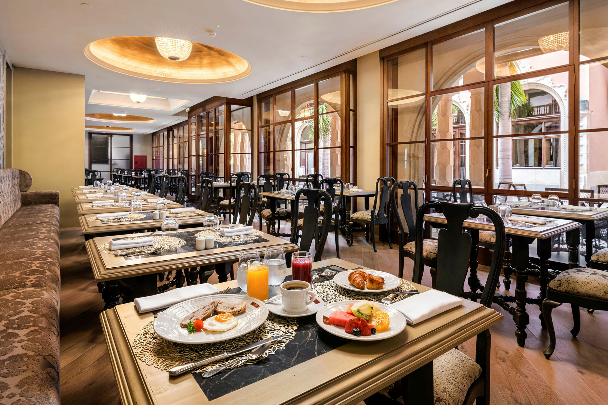 Bild av en restaurang med eleganta sittplatser och fönster samt bord dukade med frukost. (AI-genererad text)