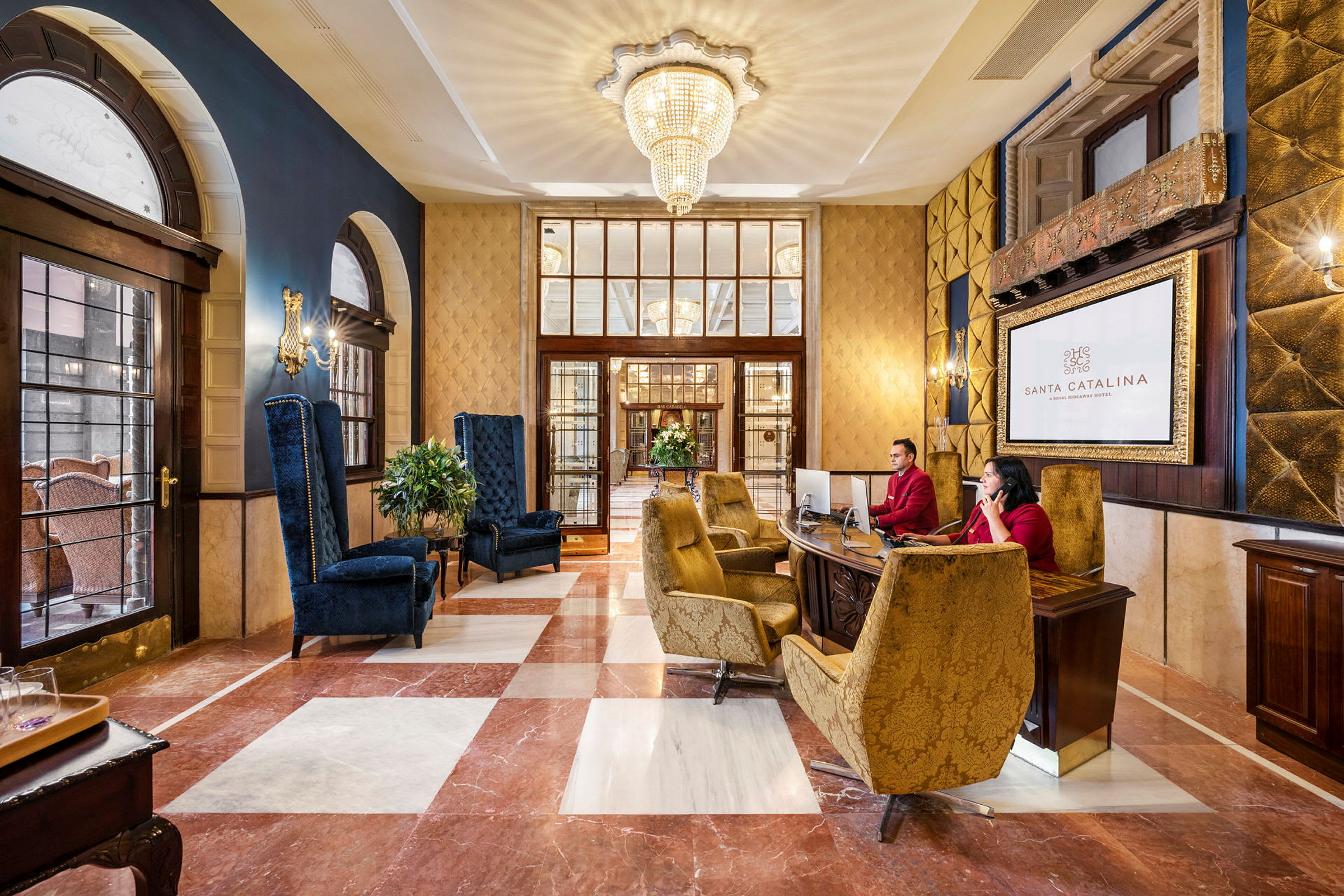 Hotelllobby med eleganta sittgrupper och reception. En stor kristallkrona hänger i taket. (AI-genererad text)