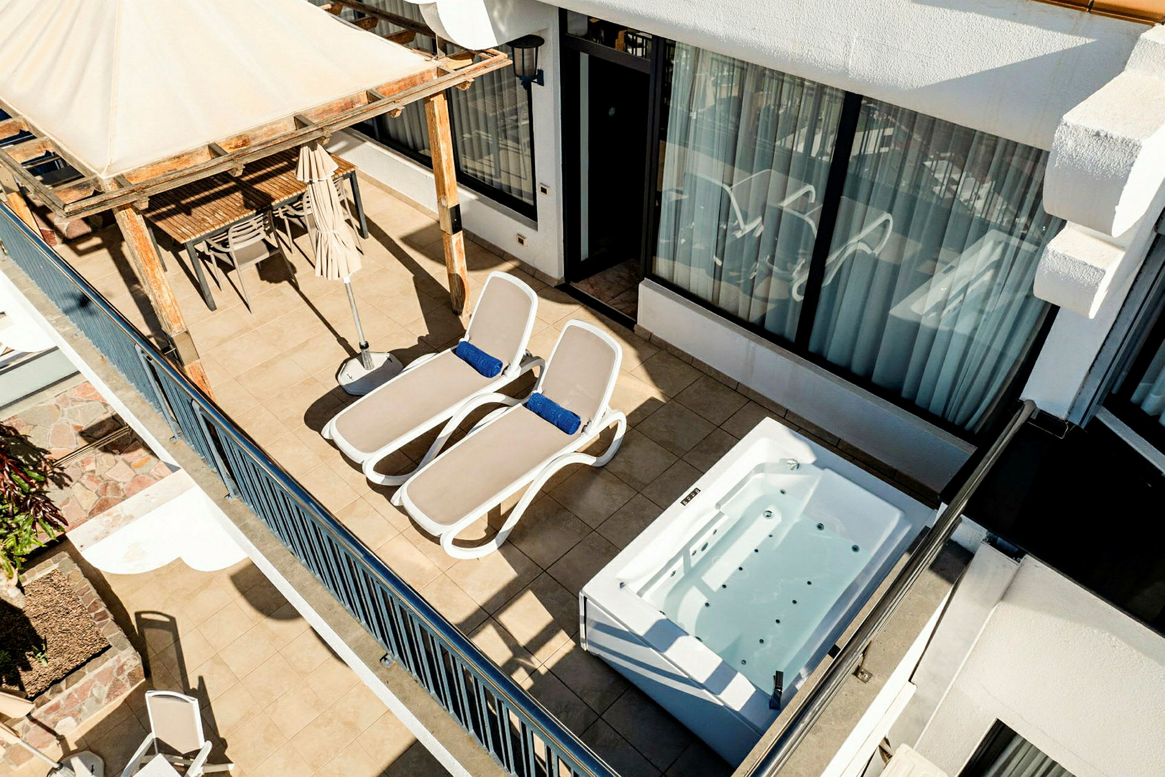 En terrass med två solstolar, en jacuzzi, och en matplats under en pergola. (AI-genererad text)