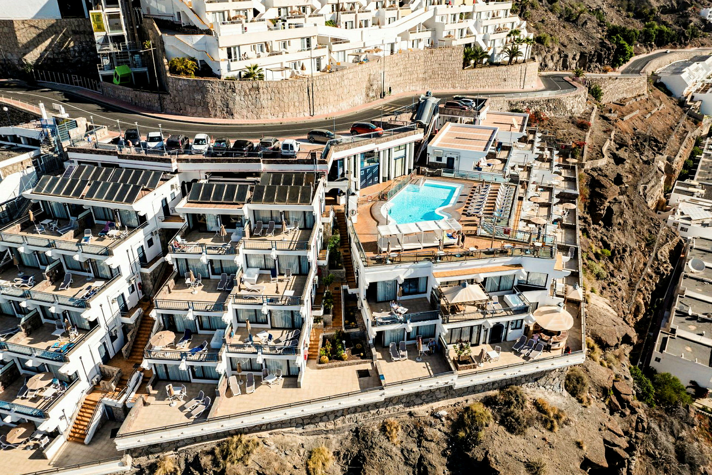 Hotellkomplex med lägenheter och en utomhuspool på en klippavsats. (AI-genererad text)