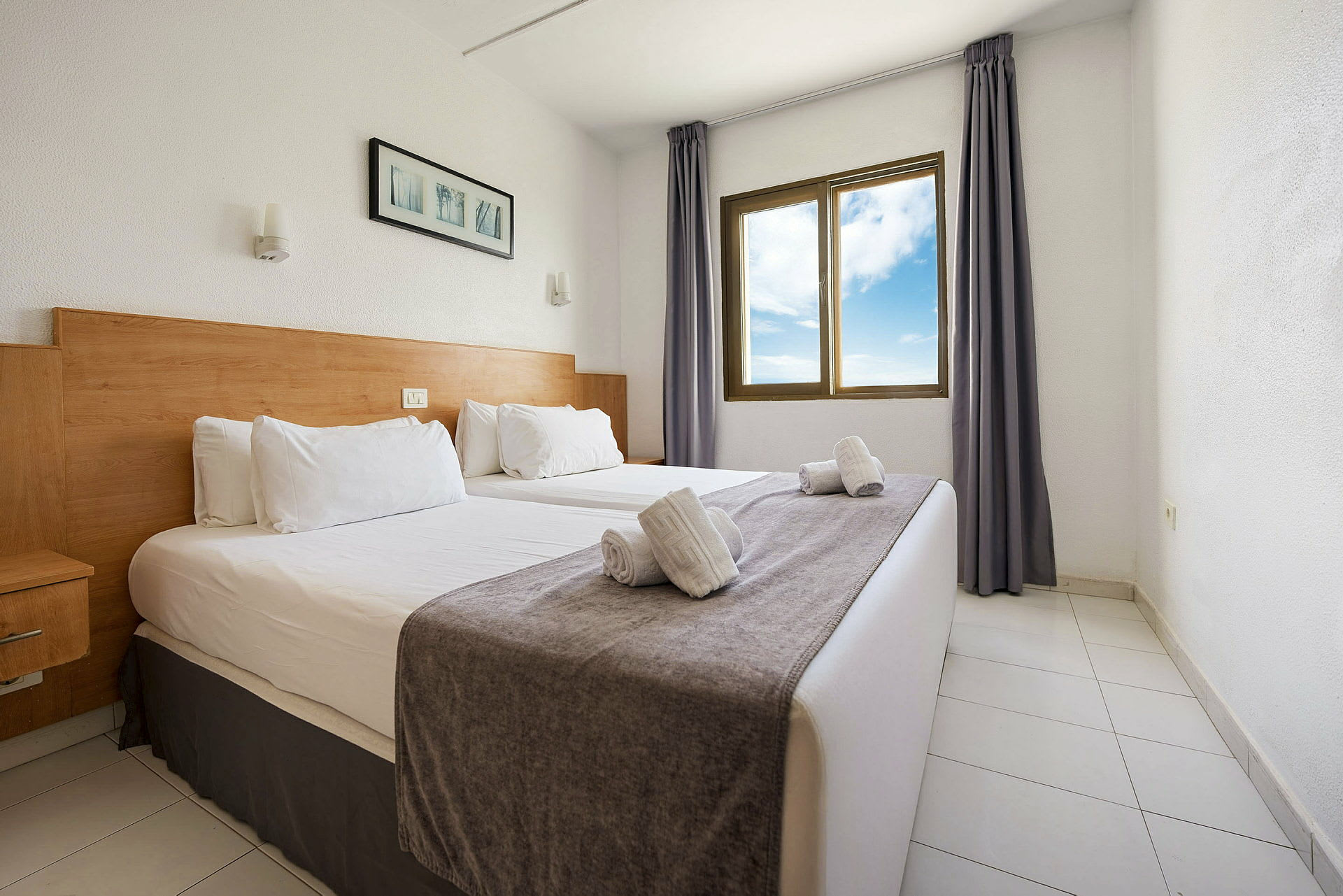 Ett hotellrum med två enkelsängar, ett fönster med utsikt och enkla dekorationer. (AI-genererad text)