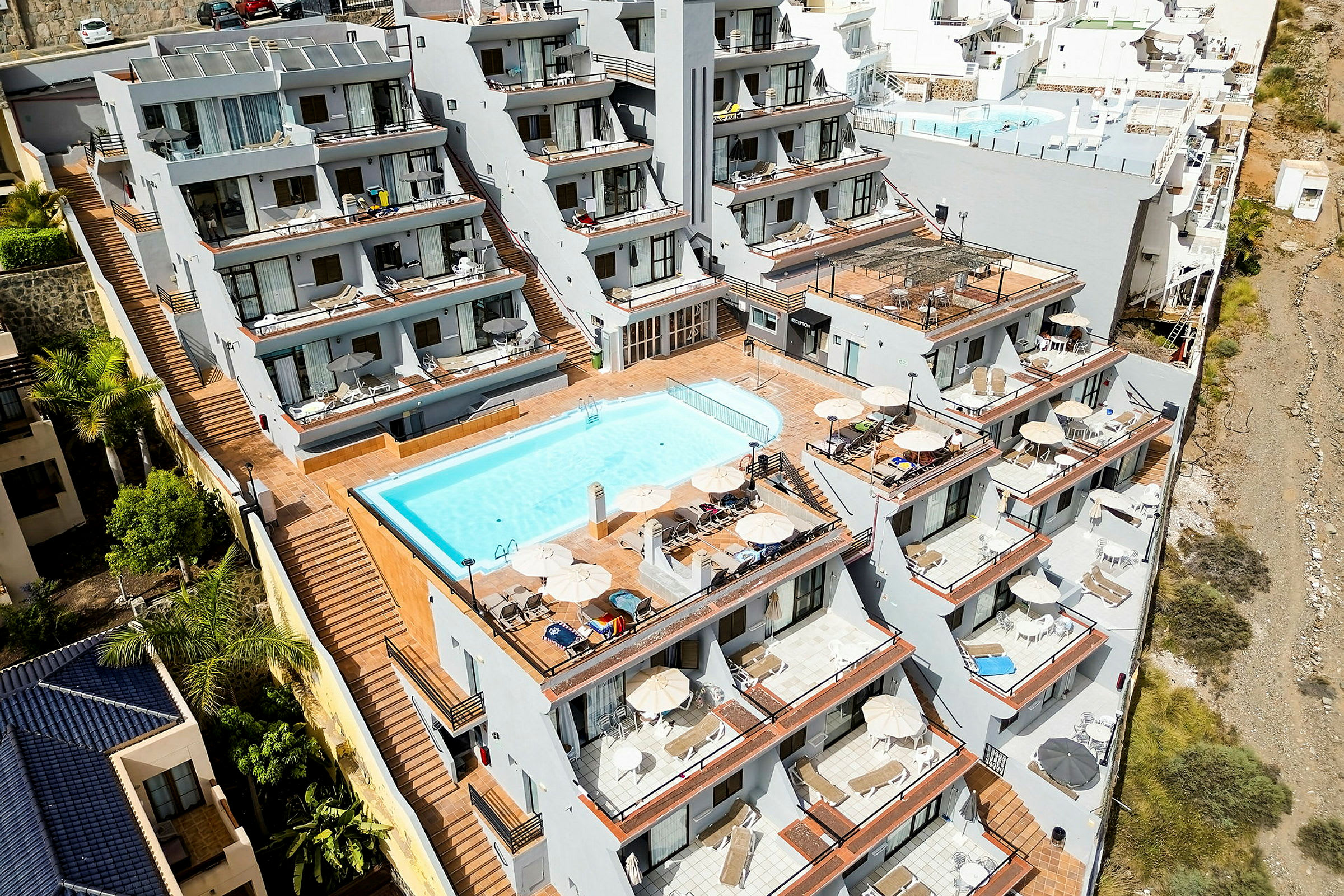 Ett hotellkomplex med flera terrasser och en pool. (AI-genererad text)