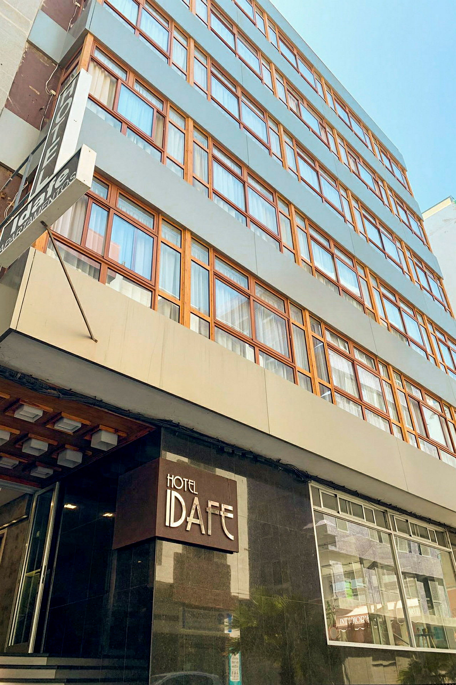 En byggnad med flera våningar och skylt med texten 'Hotel Idafe' vid entrén. (AI-genererad text)
