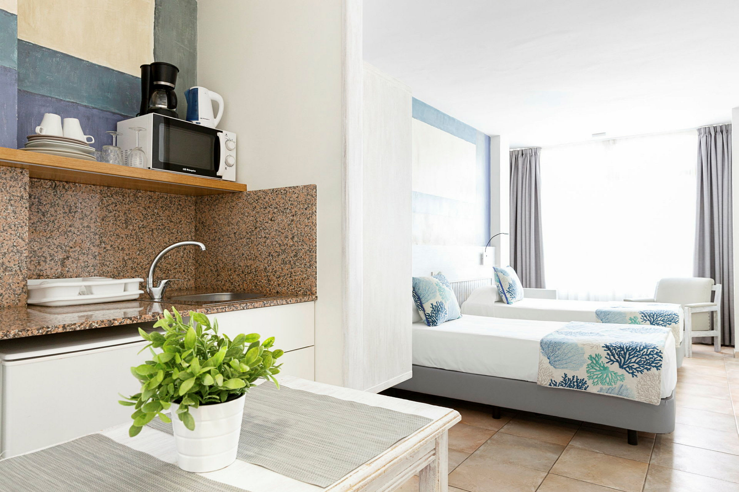 Interiör av ett hotellrum med ett pentry och två enkelsängar. (AI-genererad text)