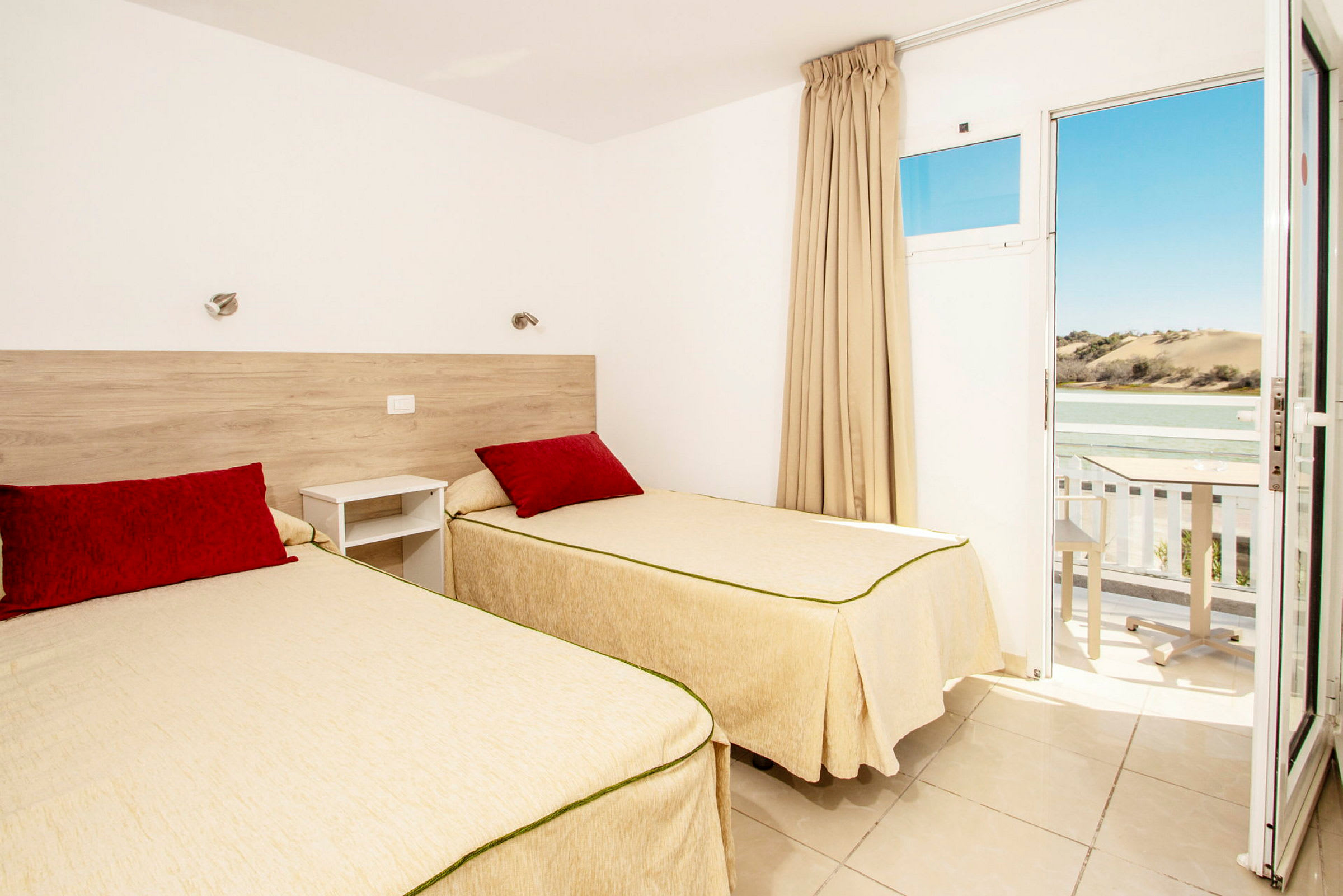 Ett hotellrum med två enkelsängar och en balkong med utsikt över landskapet. (AI-genererad text)