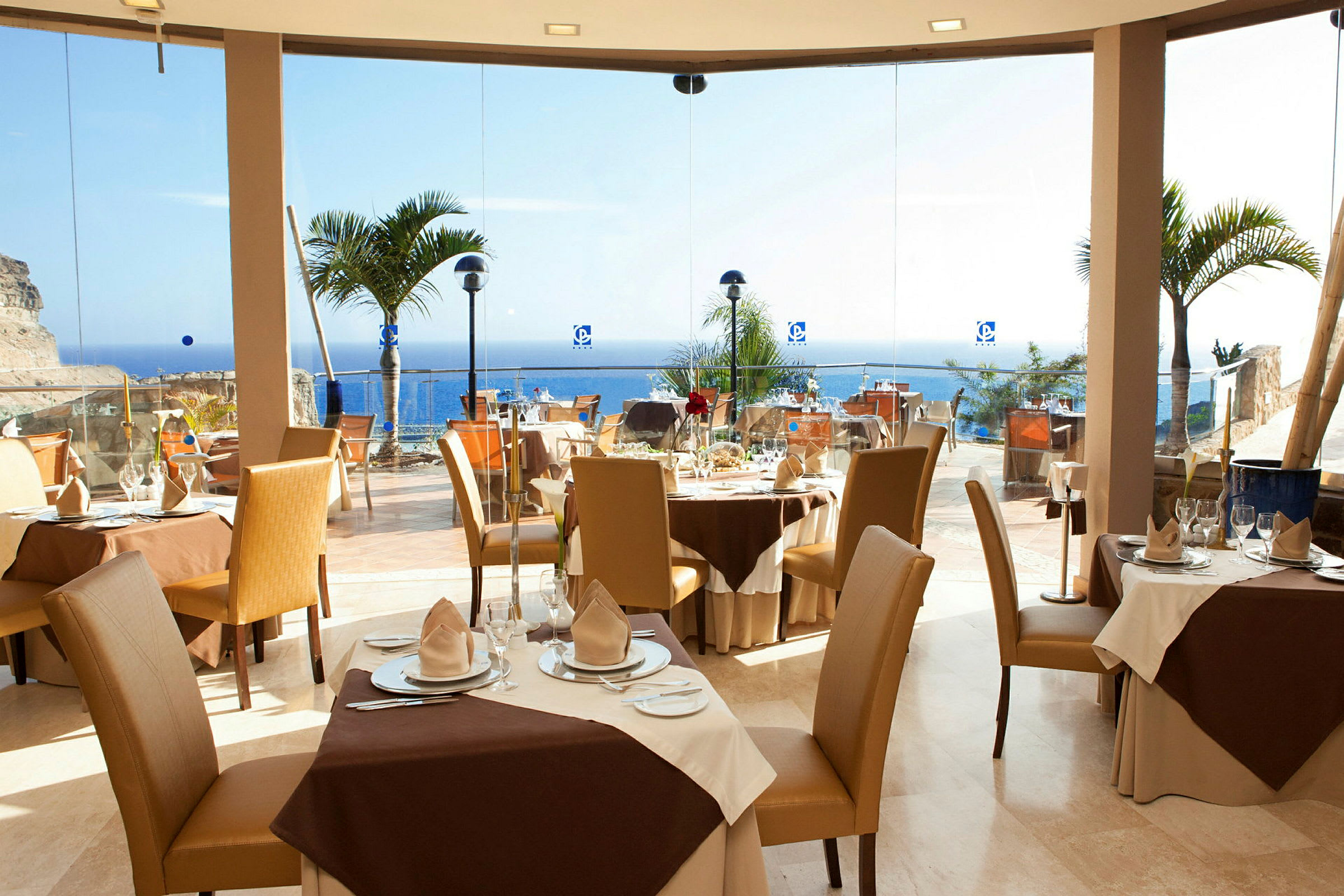 En restaurang med dukade bord, stora fönster och utsikt över havet. (AI-genererad text)