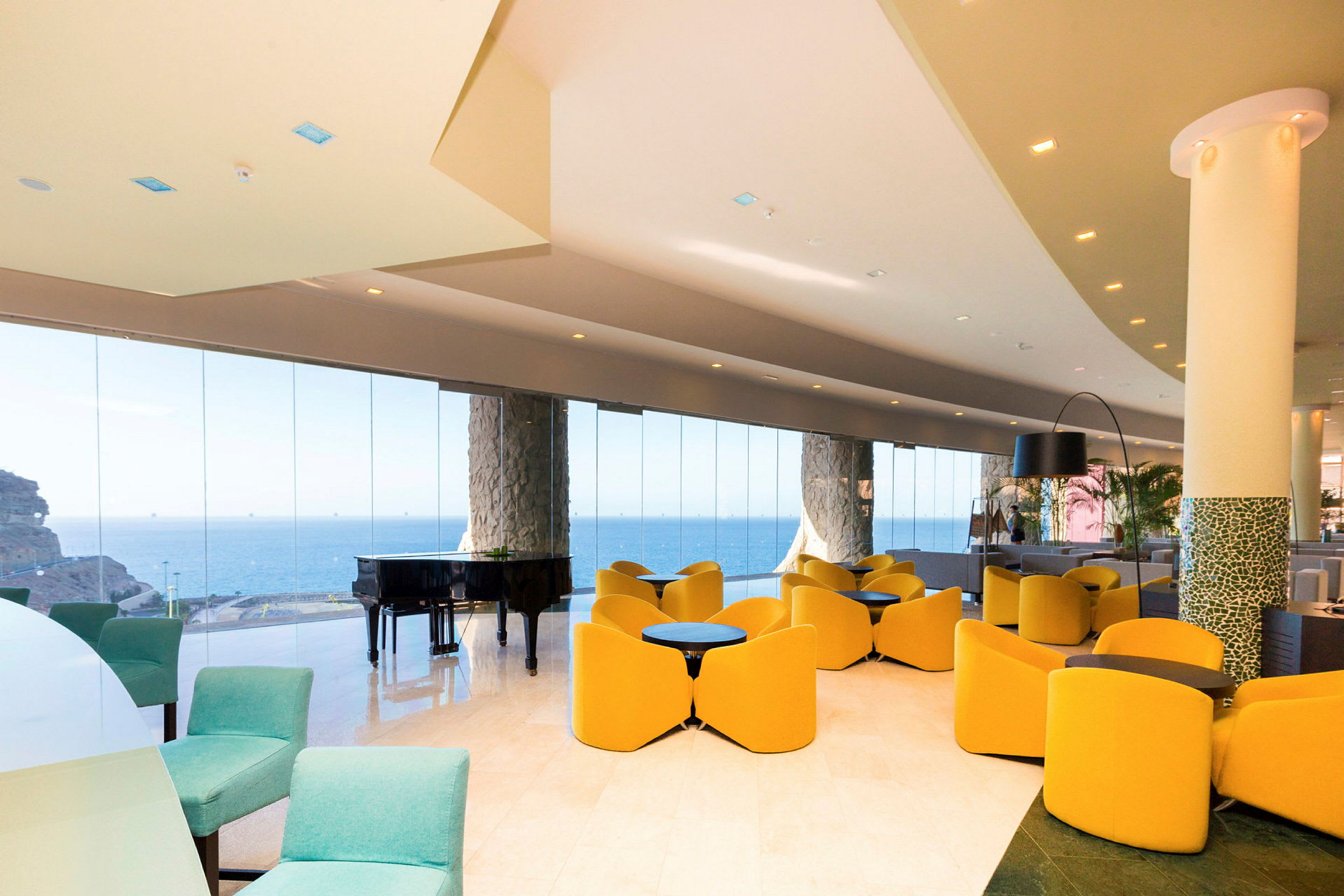 En hotellobby med moderna möbler, stora glasväggar och utsikt över havet. (AI-genererad text)