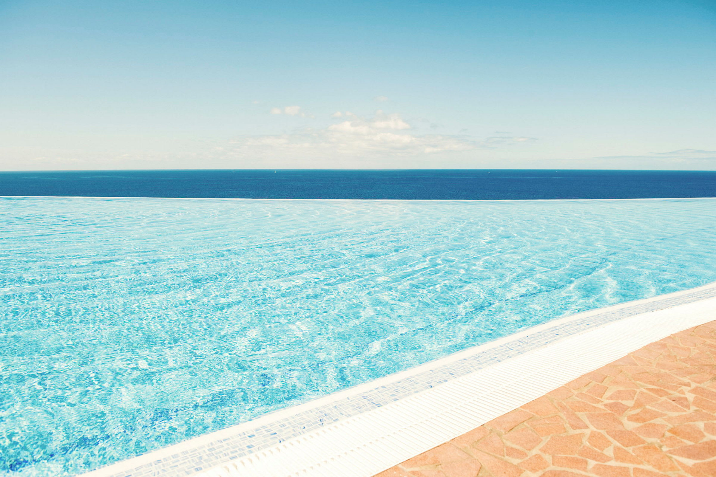 En infinitypool med utsikt över havet under en klarblå himmel. (AI-genererad text)