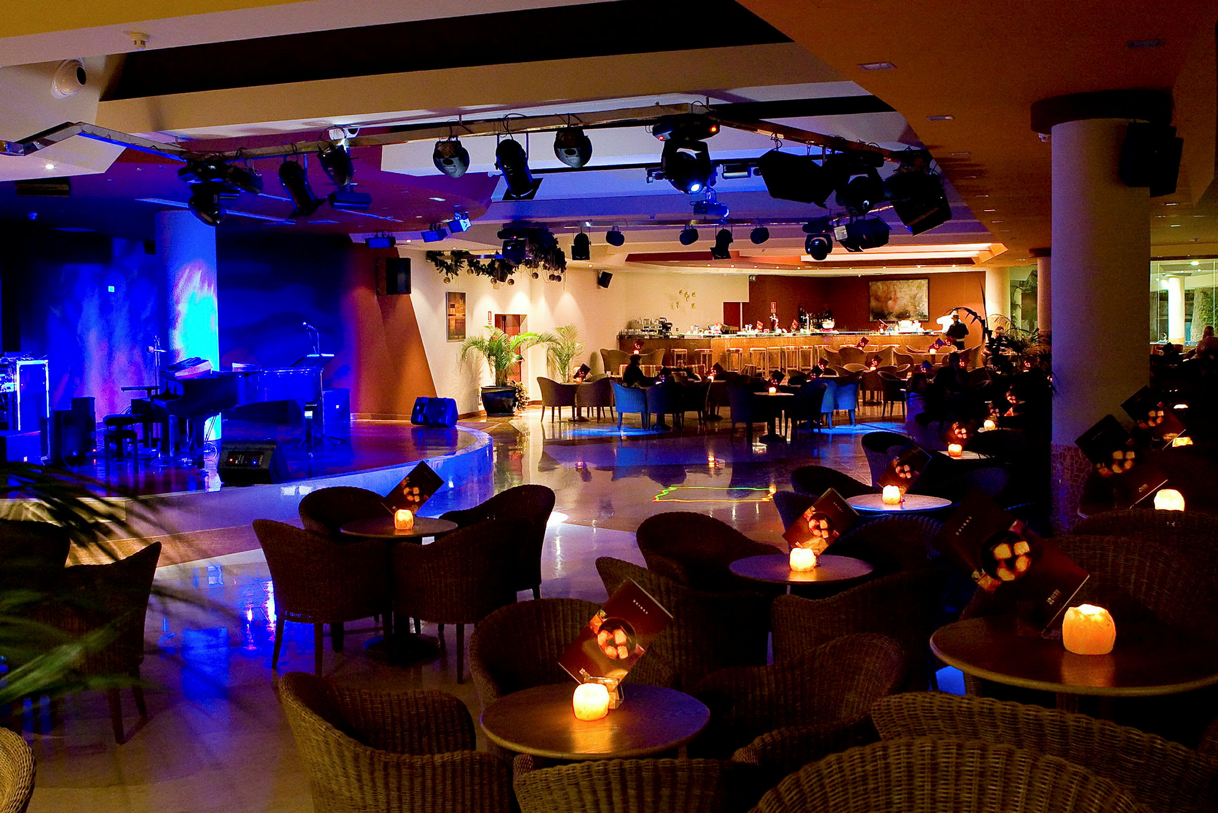Interiör av en upplyst bar och scen med sittplatser runt små bord. (AI-genererad text)