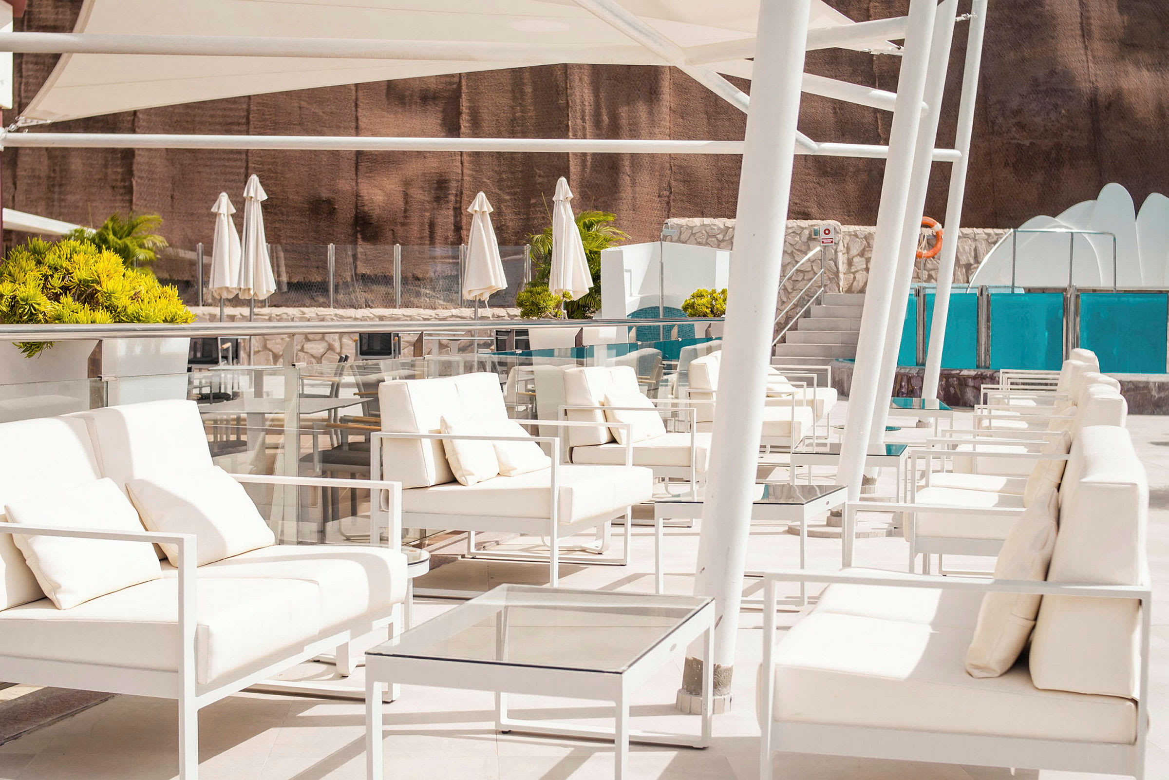 Loungeområde med vita möbler och parasoller nära en pool. (AI-genererad text)