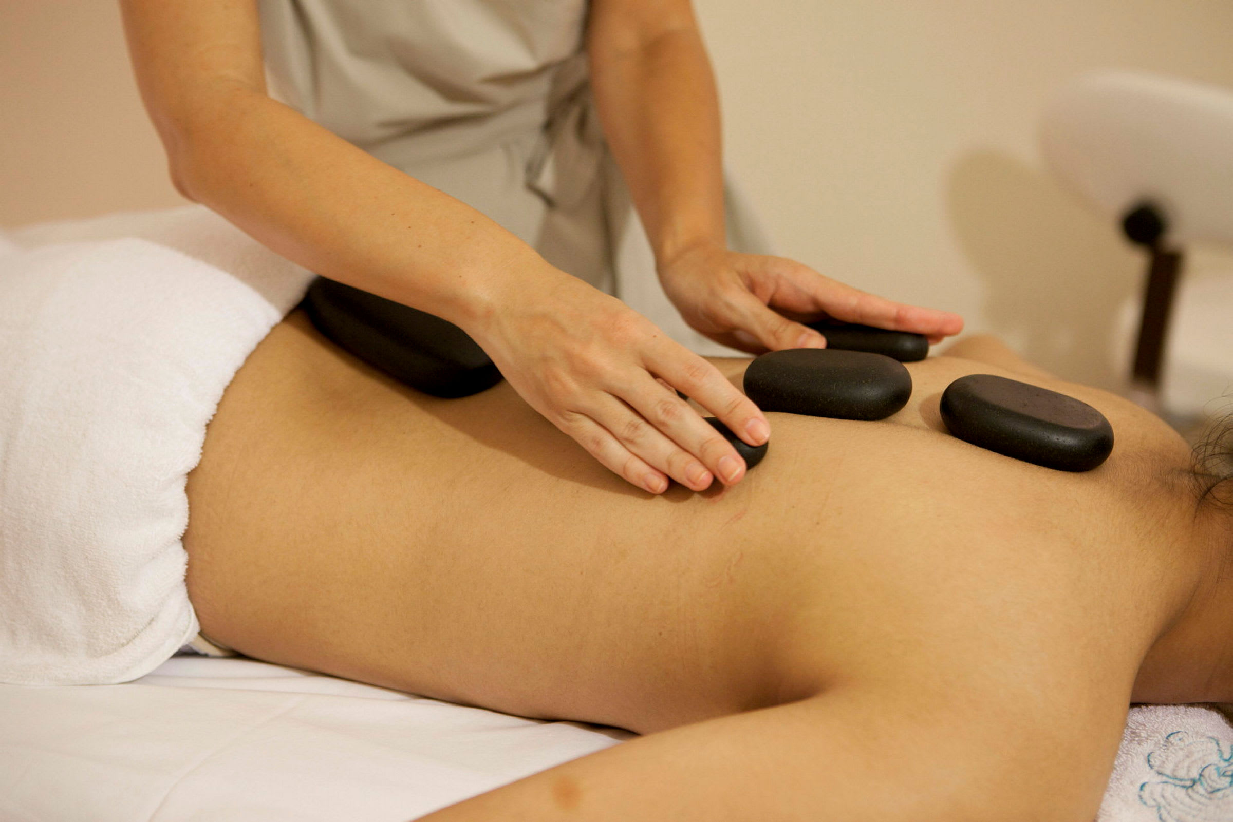 En person får hot stone-massage på ryggen. (AI-genererad text)