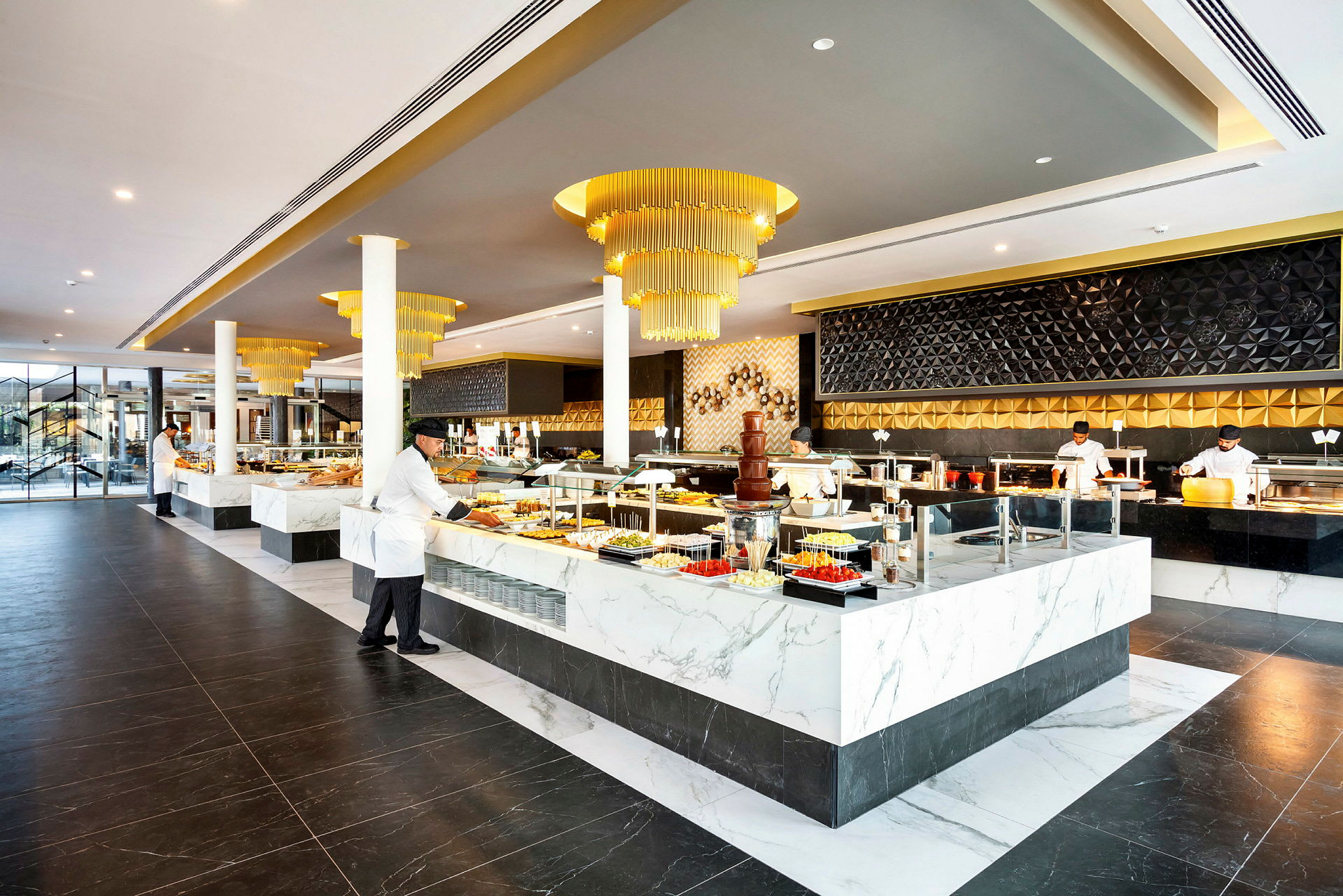 En elegant restaurangbuffé med moderna inredningsdetaljer och marmorbeklädda stationer fyllda med olika matalternativ. (AI-genererad text)
