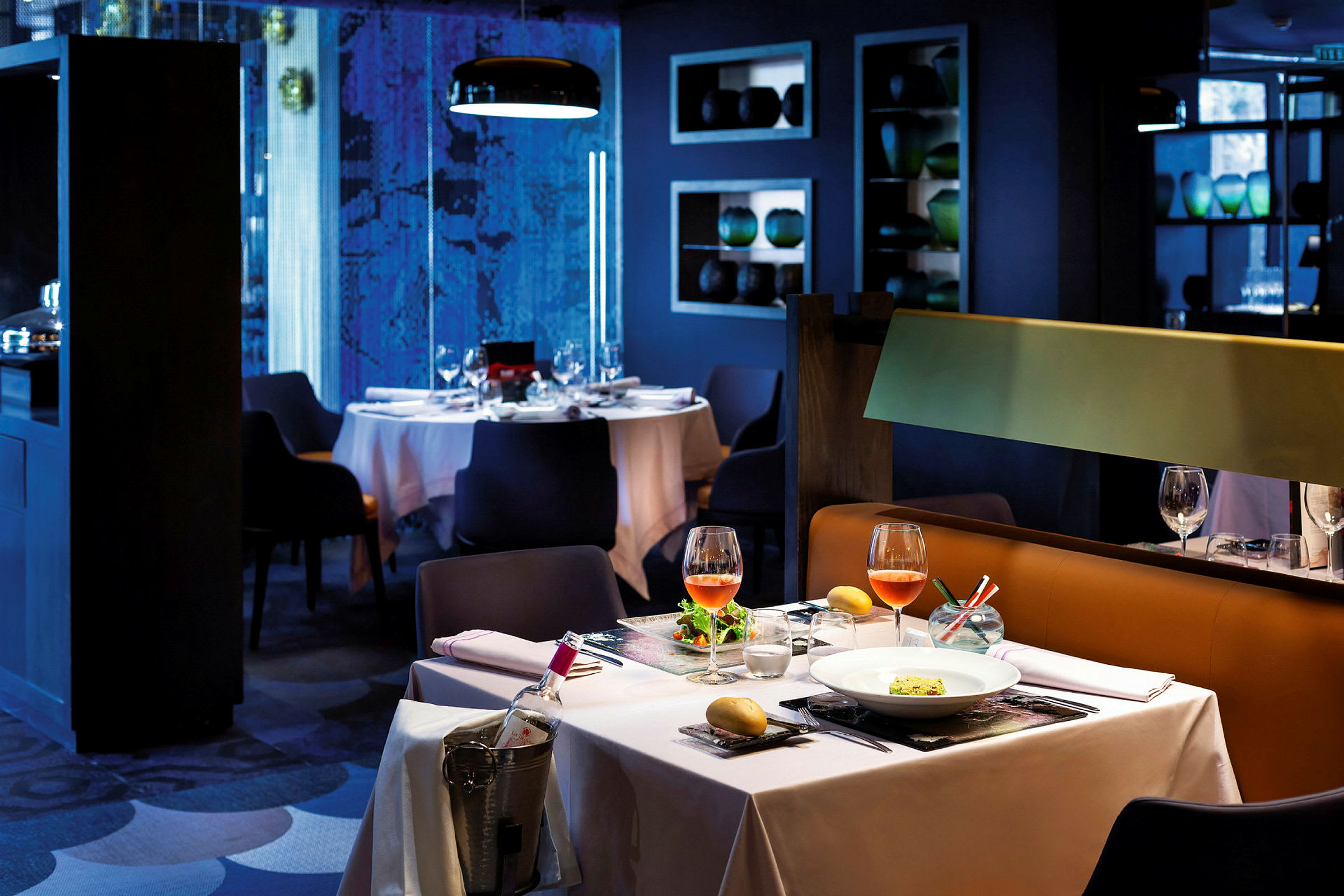 Ett elegant restaurangbord med vit duk, två vinglas och en upplagd rätt. En iskyld vinflaska står vid sidan. (AI-genererad text)