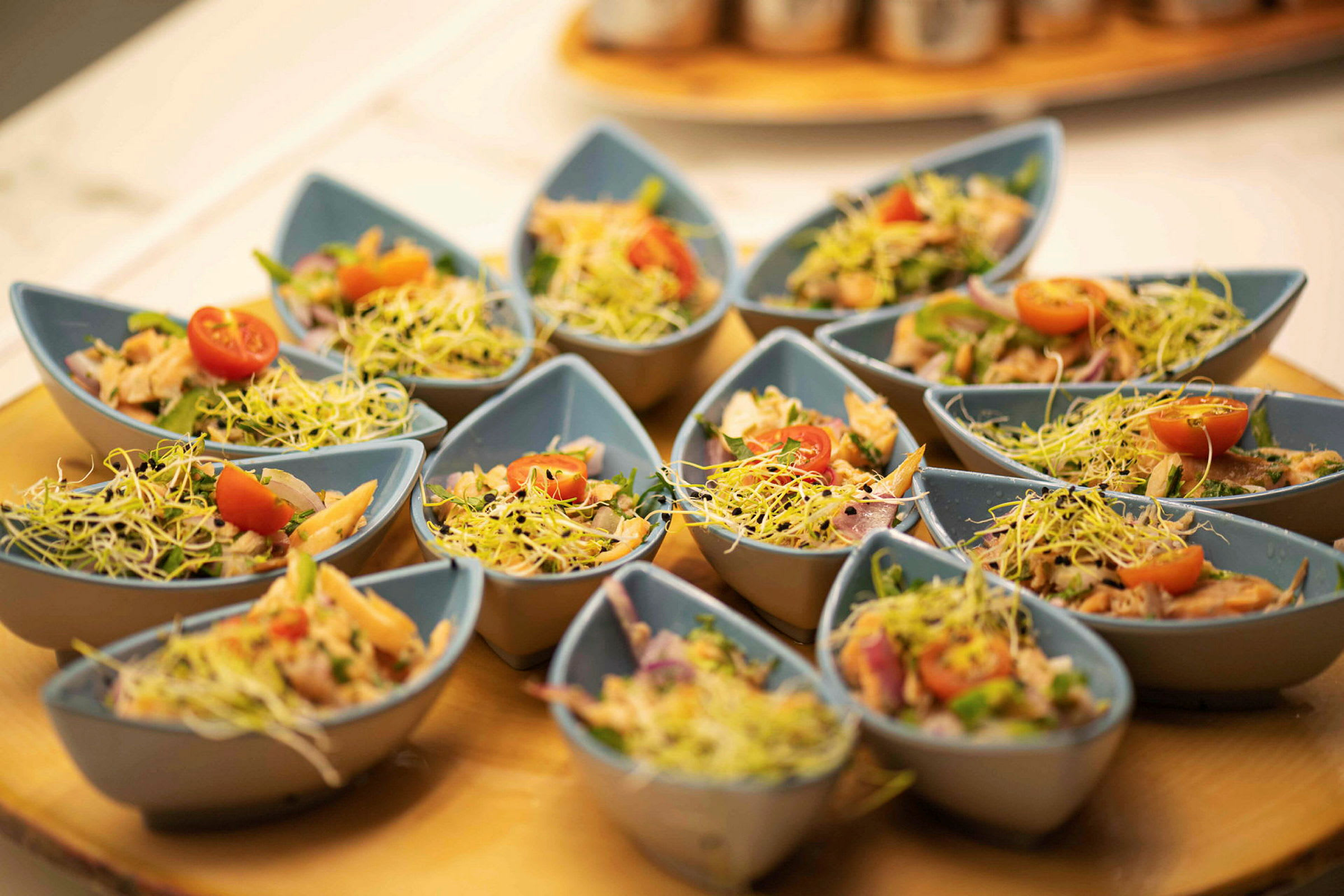 Små portioner av sallad i blå skålar med grönsaker och groddar. (AI-genererad text)