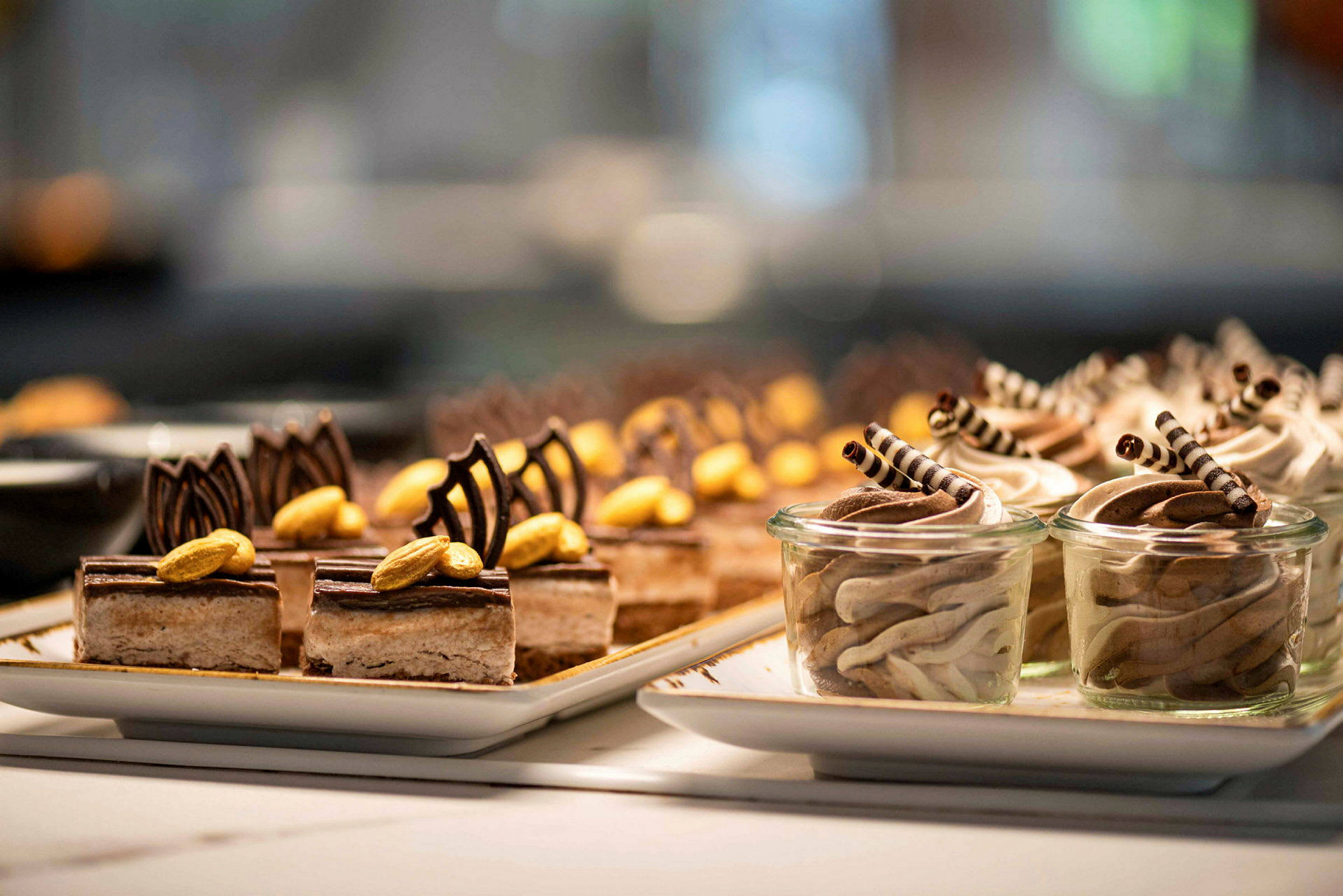 Tallrikar med små desserter dekorerade med choklad och nötter. (AI-genererad text)