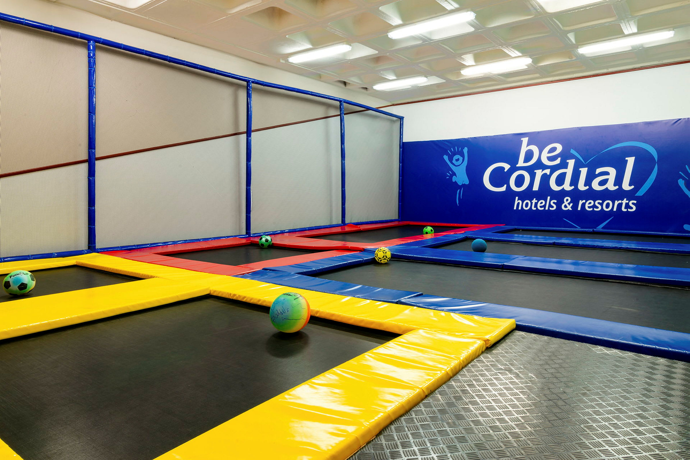 En inomhus trampolinpark med färgglada trampoliner och bollar. (AI-genererad text)