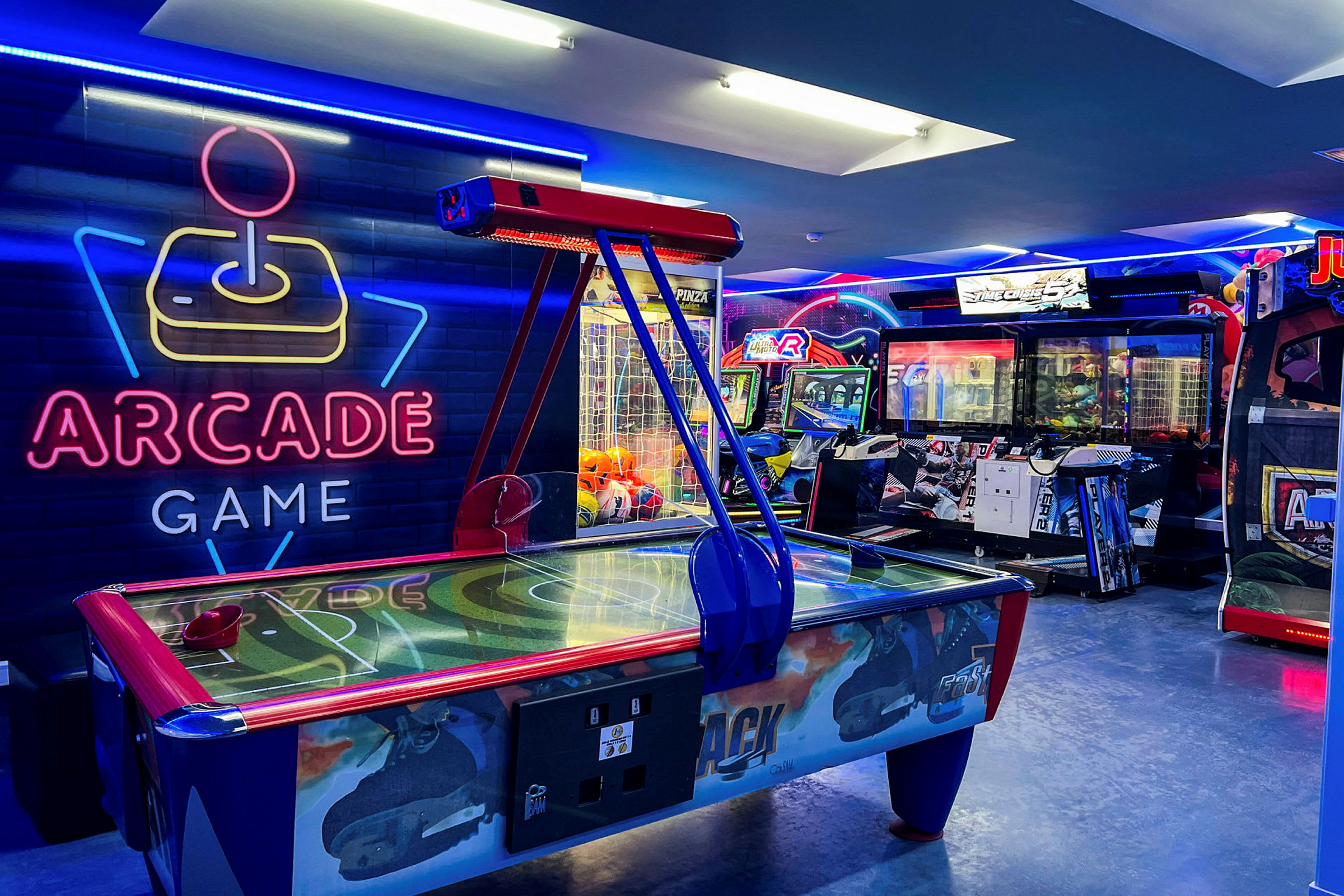 Neonbelyst arkadspelsrum med air hockey-bord och spelautomater. (AI-genererad text)