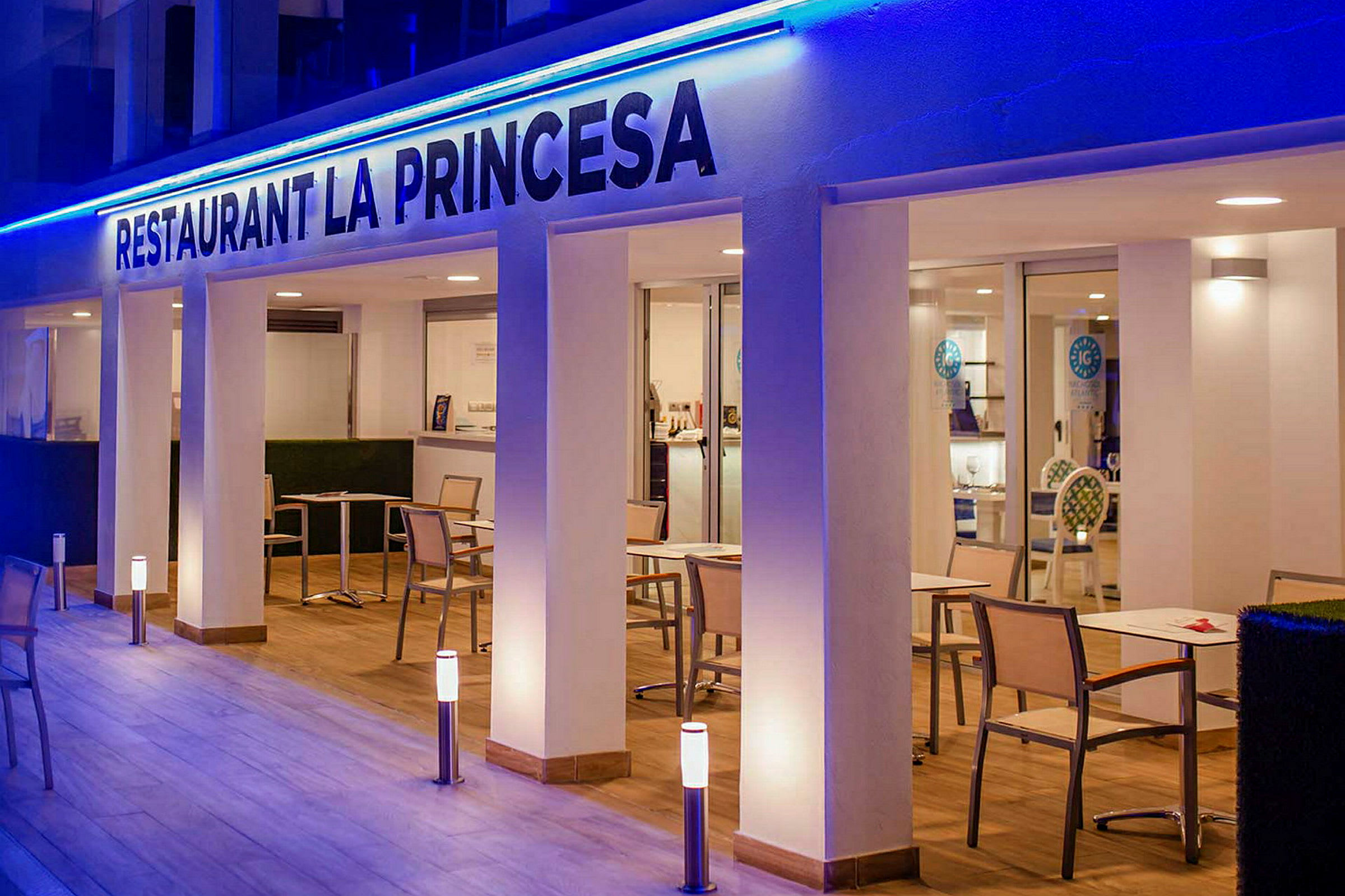 Restaurang La Princesa med bord och stolar på en belyst altan. (AI-genererad text)