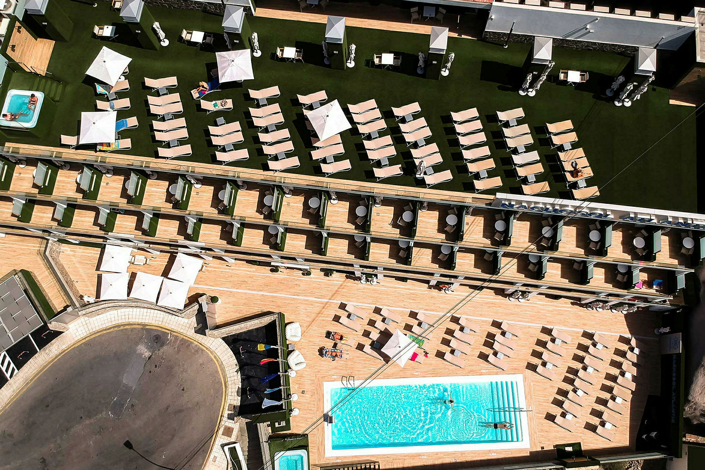 Flygfoto av hotellområde med pool, solstolar och parasoll. (AI-genererad text)