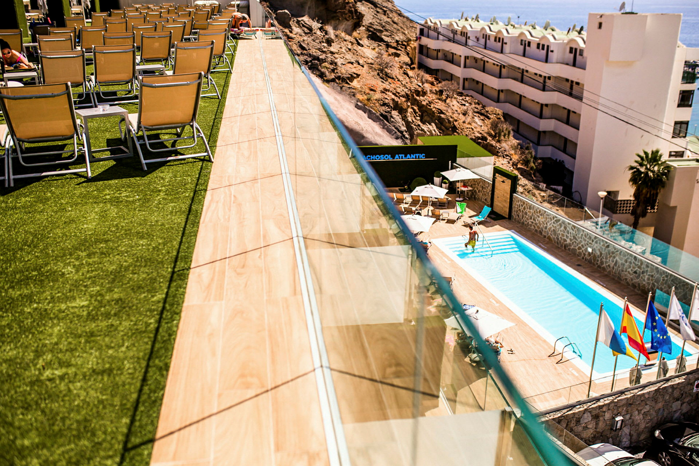 En pool med solstolar på olika nivåer vid en byggnad. (AI-genererad text)