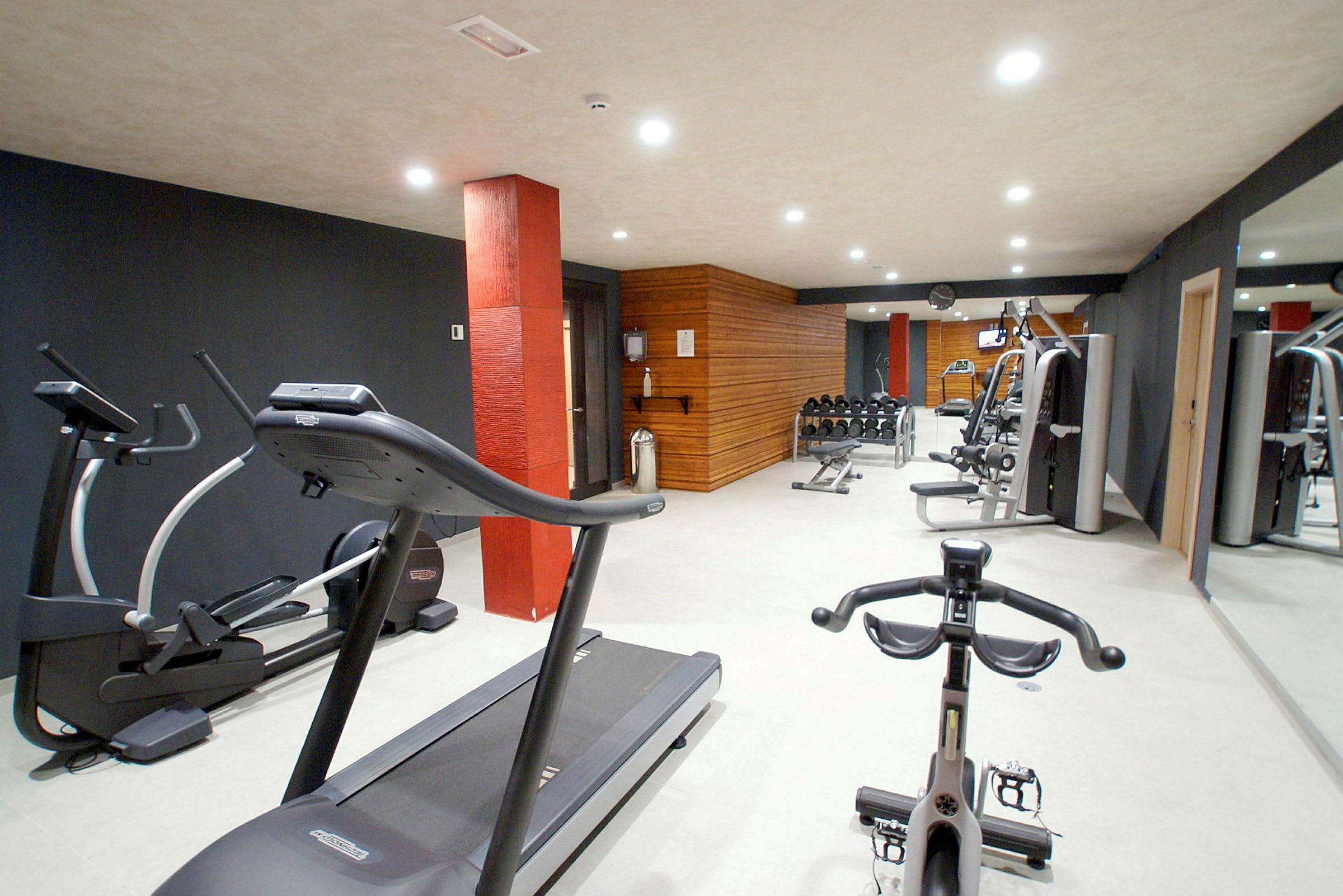 Ett gym med träningsmaskiner inklusive löpband och styrketräningsutrustning. (AI-genererad text)