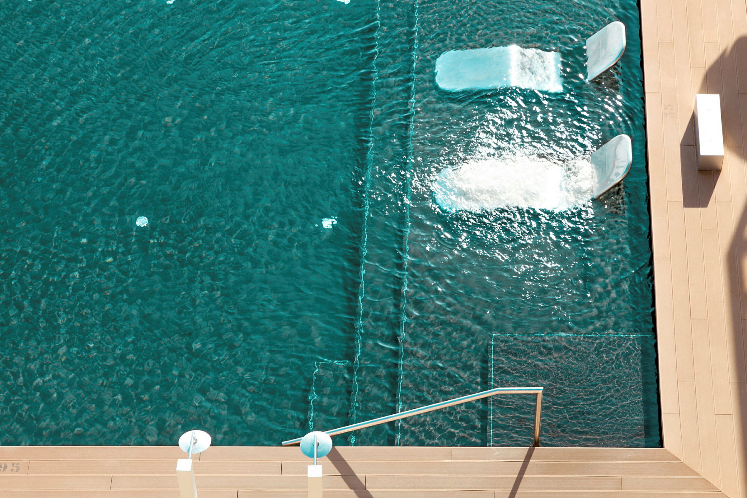 Pool med två inbyggda liggplatser där vatten strömmar över. (AI-genererad text)