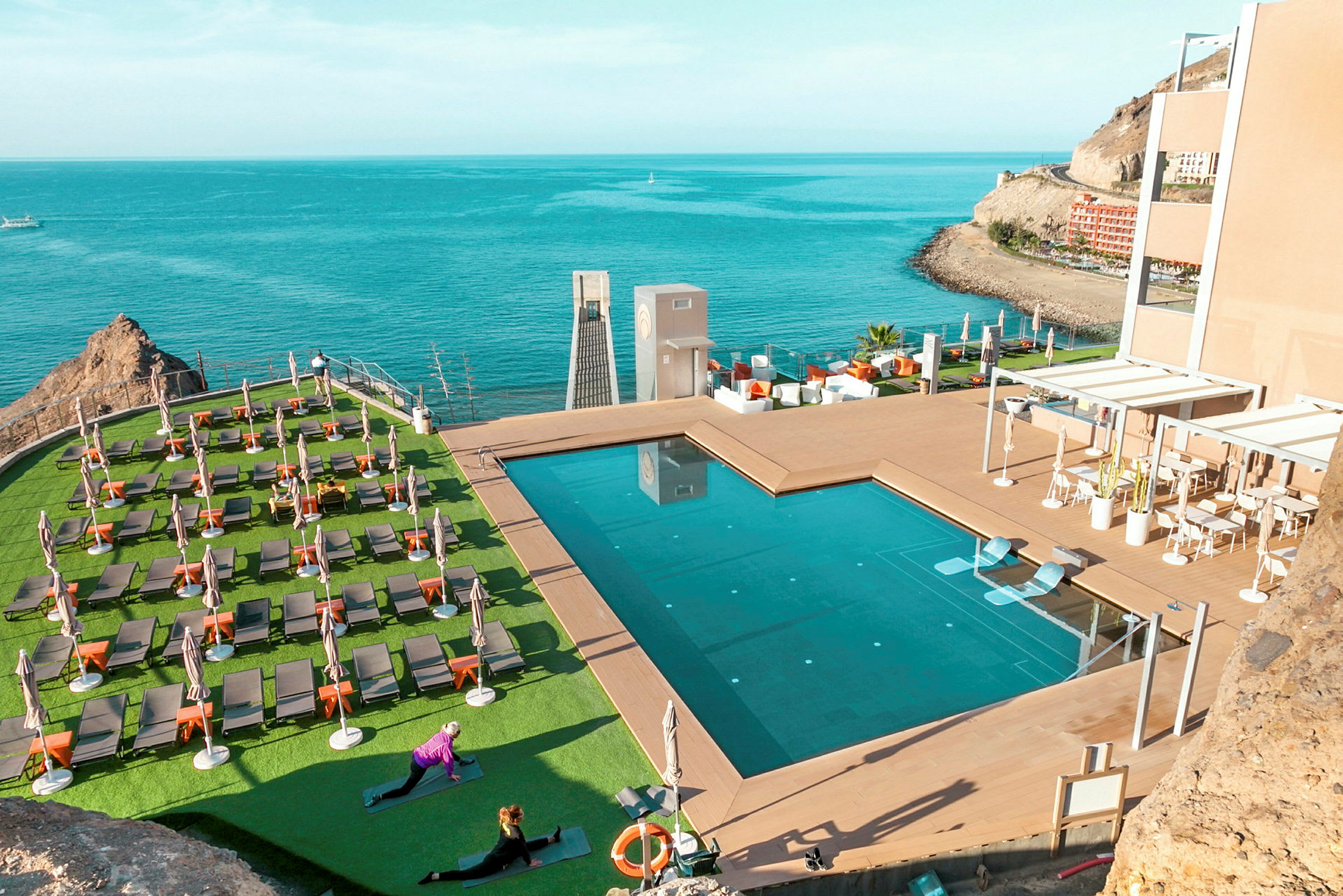 En pool med omgivande solstolar vid havet. (AI-genererad text)