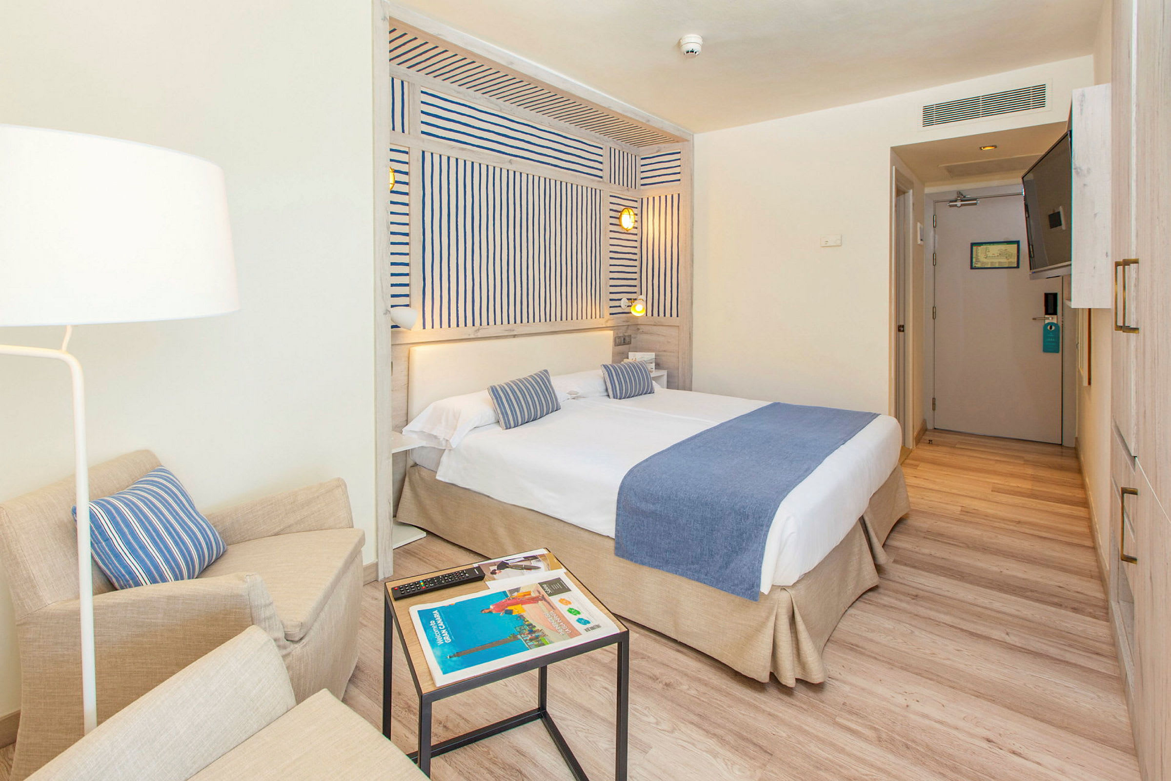 Ett hotellrum med en dubbelbädd, blå sängkläder och modern inredning. (AI-genererad text)