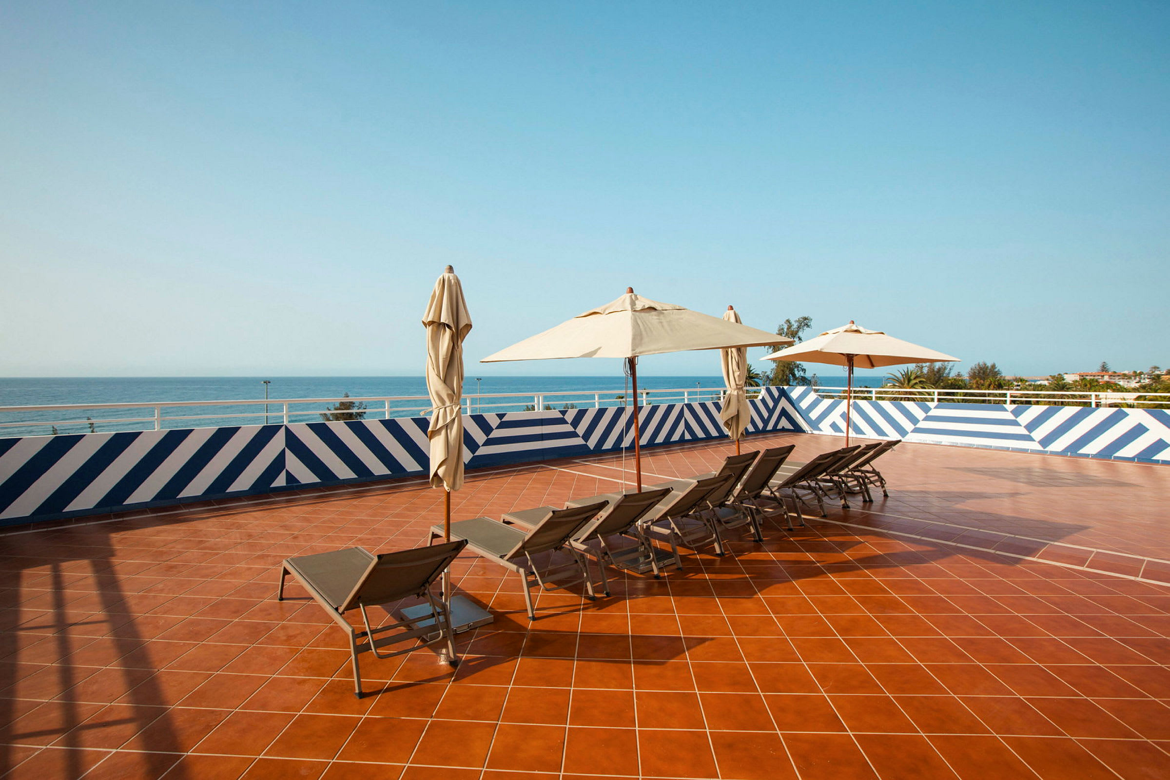 Solterrass med solstolar och parasoll, utsikt över havet. (AI-genererad text)