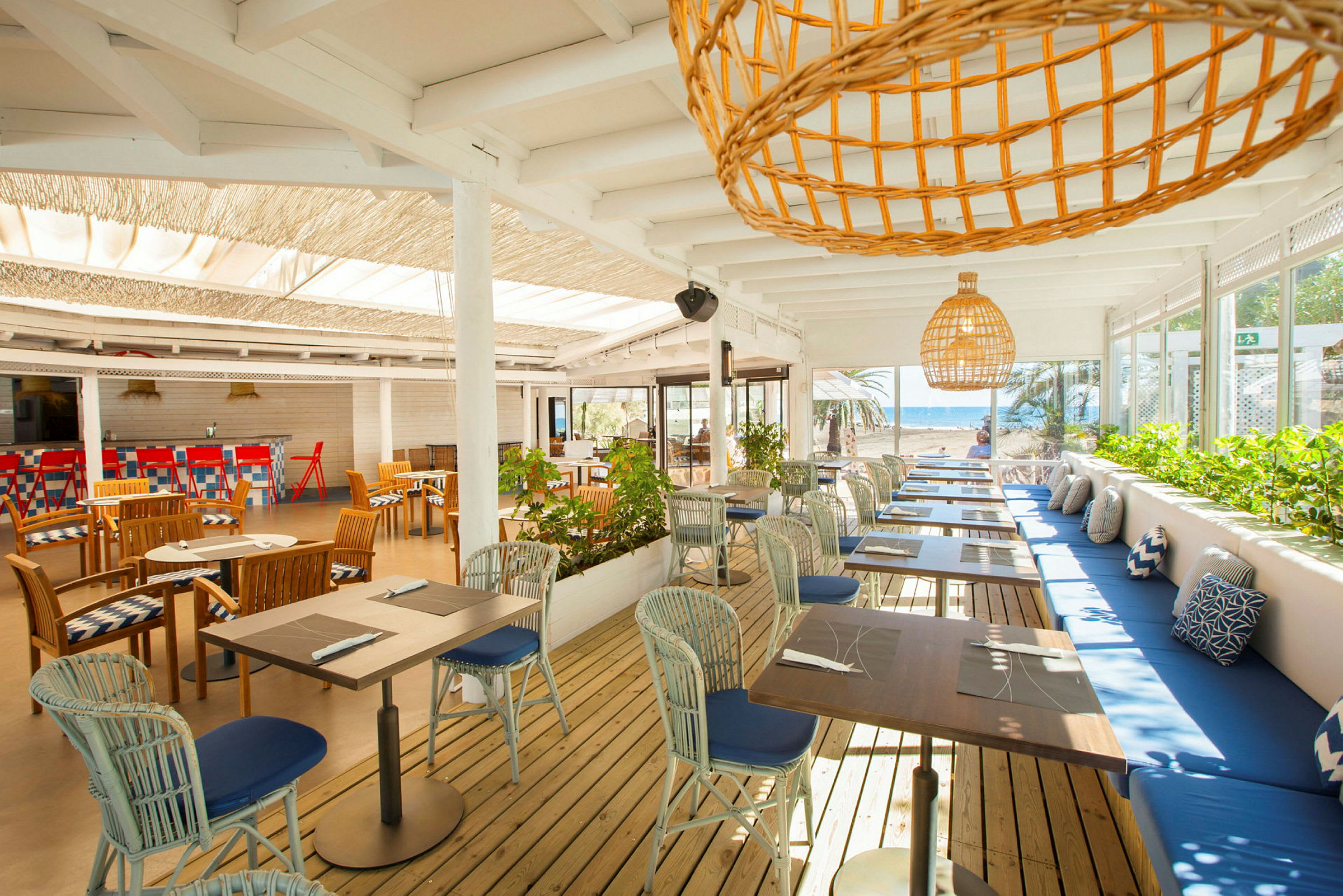 En öppen restaurang med bord och stolar samt havsutsikt. (AI-genererad text)