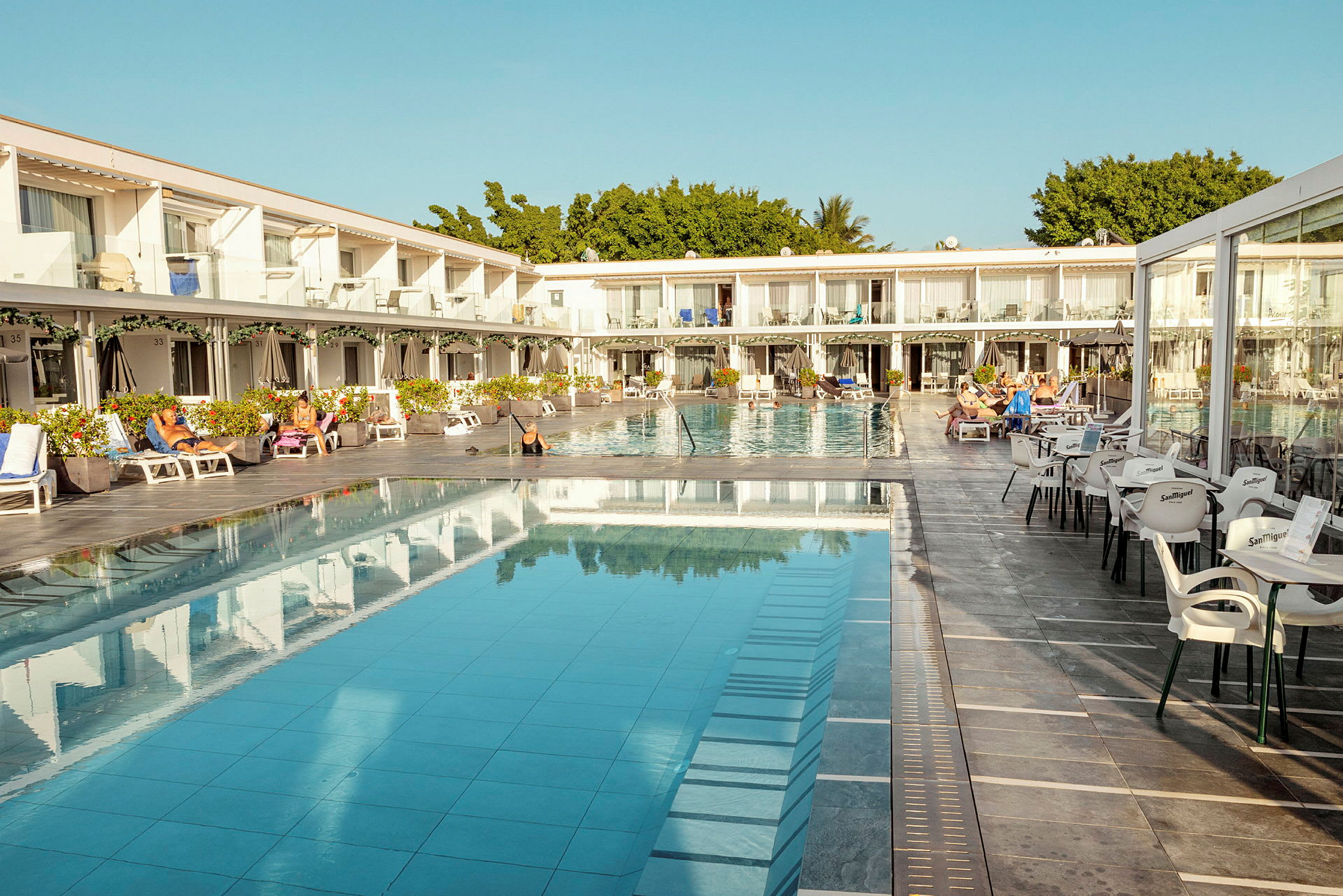 Hotellområde med pool, solstolar och sittplatser. (AI-genererad text)