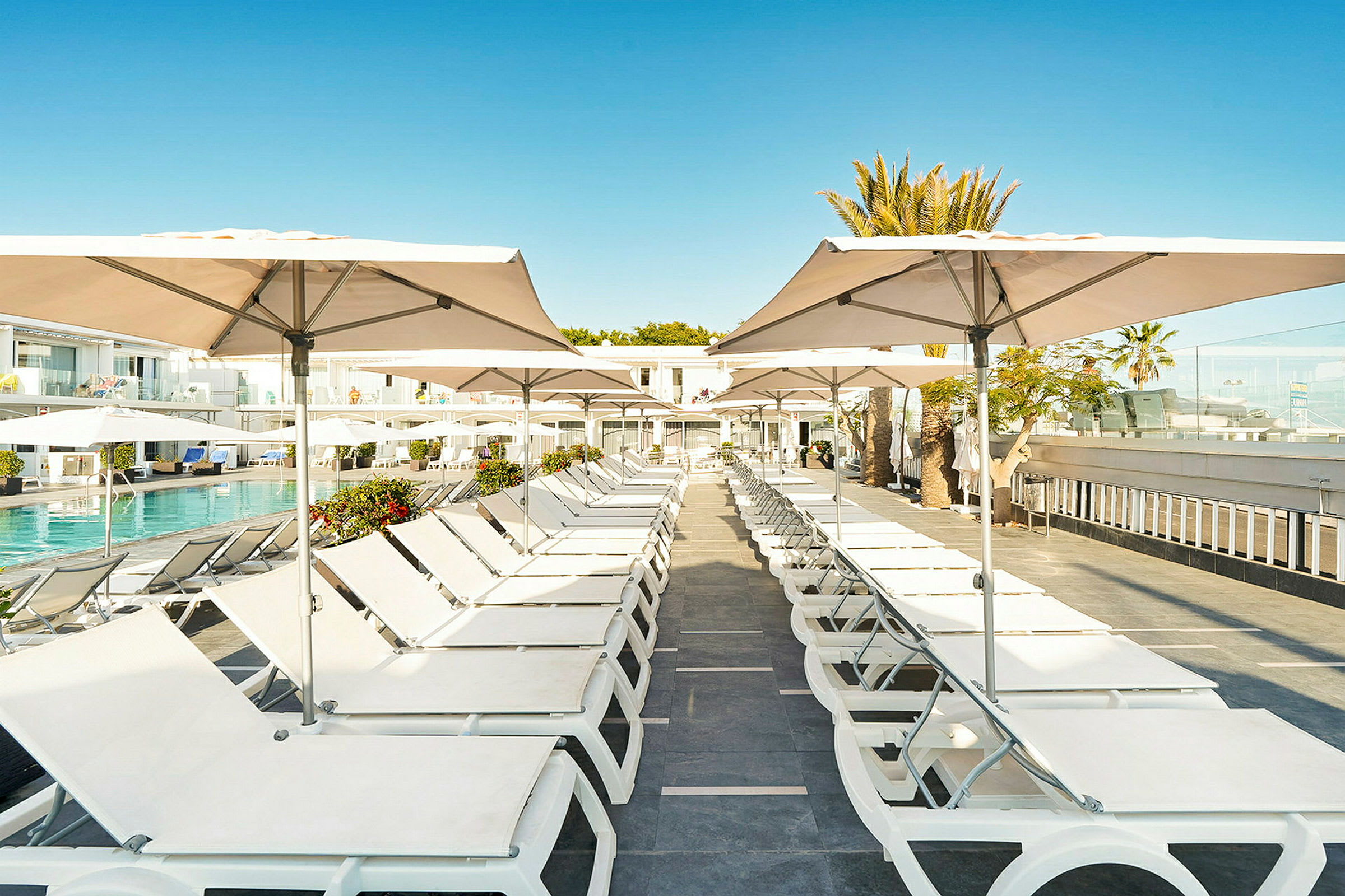 Solstolar med parasoller vid en pool. (AI-genererad text)