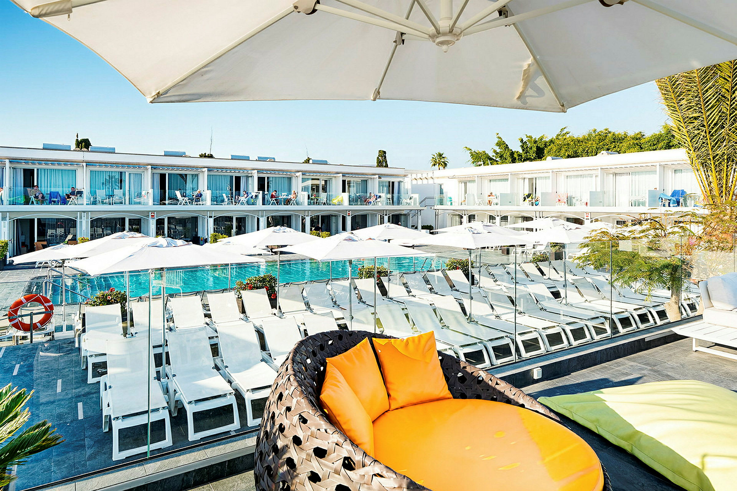 Bild på hotellområde med solstolar, parasoller och pool. (AI-genererad text)