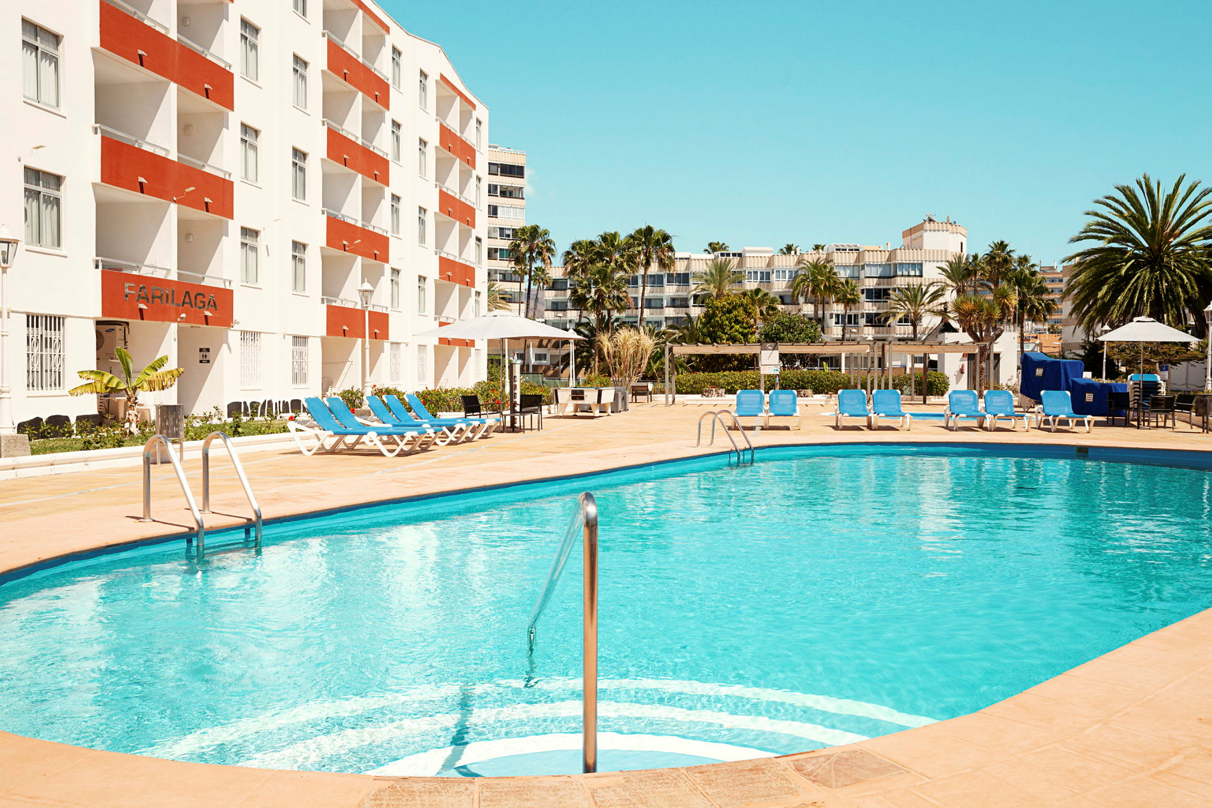 En utomhuspool med solstolar vid ett hotell. (AI-genererad text)