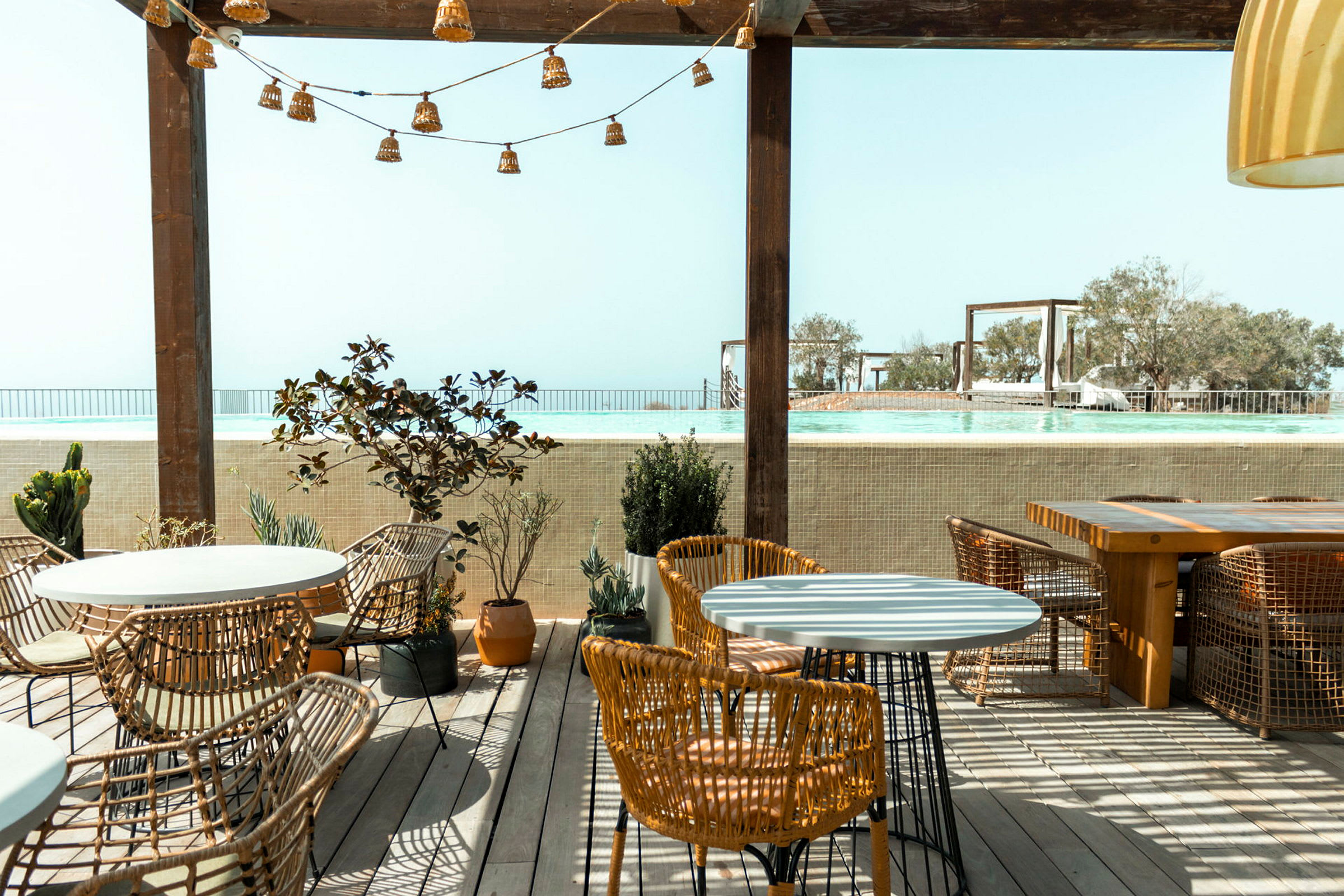 Utomhus restaurangområde med utsikt över en pool och himmel. (AI-genererad text)
