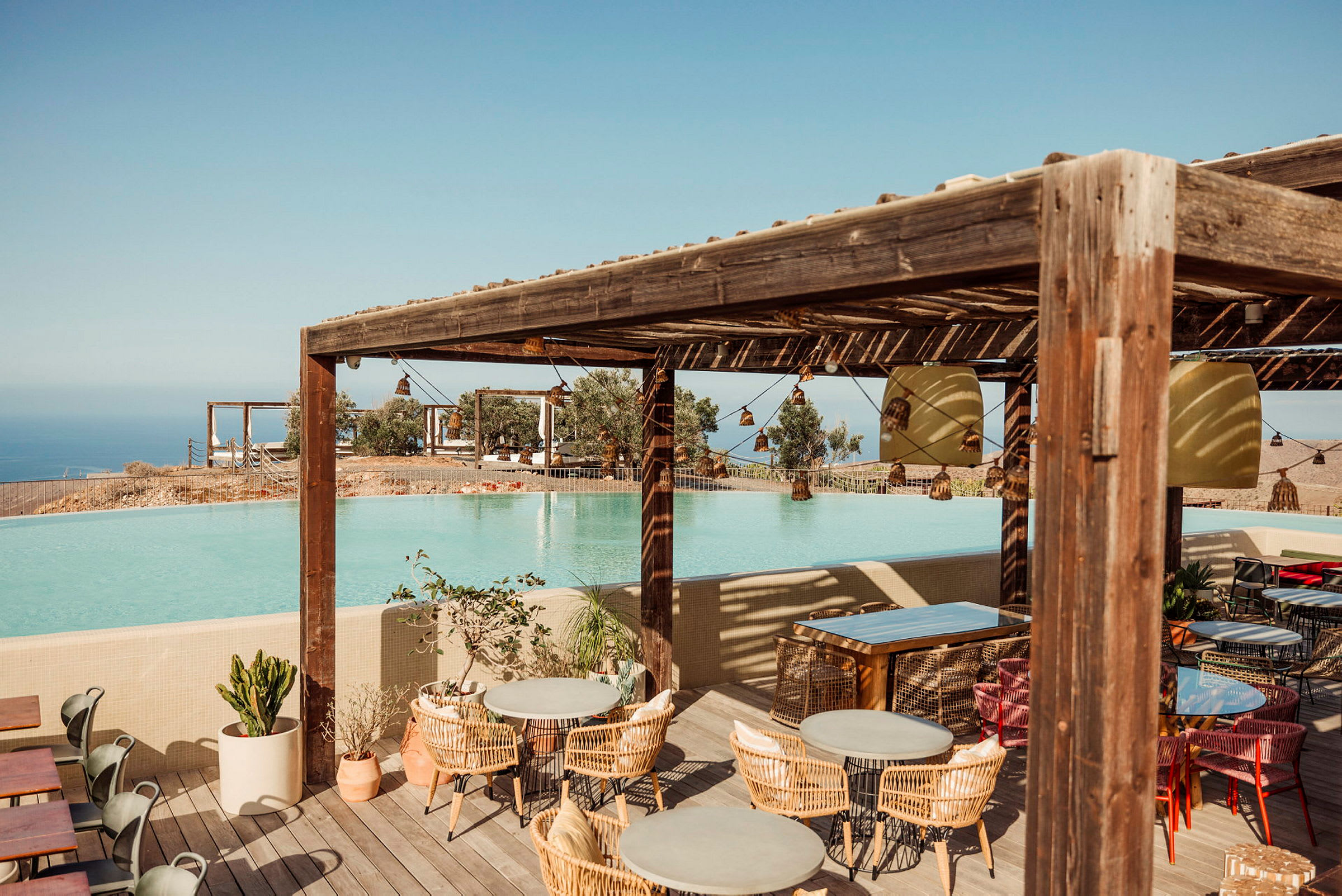 En utomhusrestaurang med utsikt över en pool och havet i bakgrunden. (AI-genererad text)
