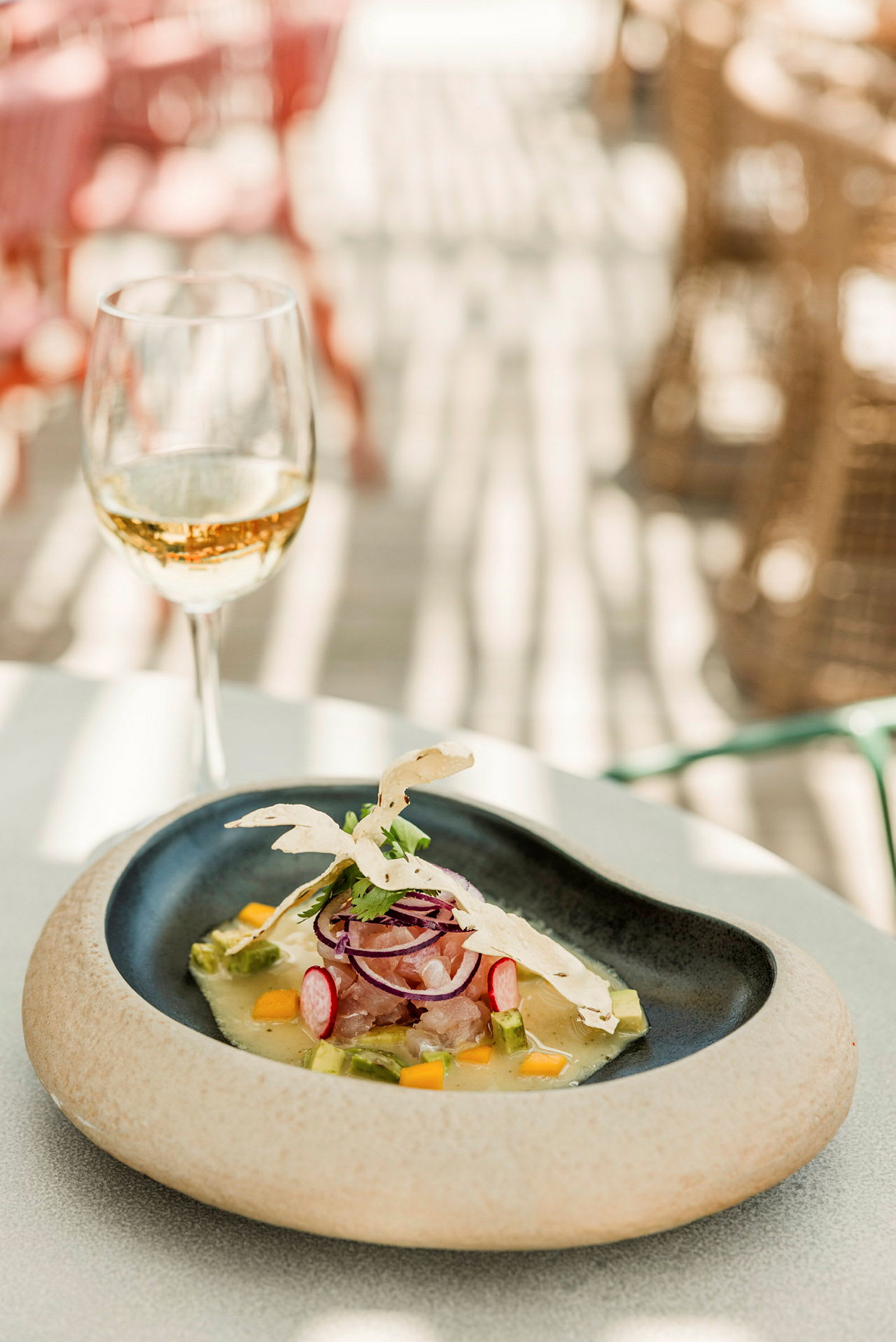 En tallrik med en maträtt och ett glas vitt vin på ett bord. (AI-genererad text)