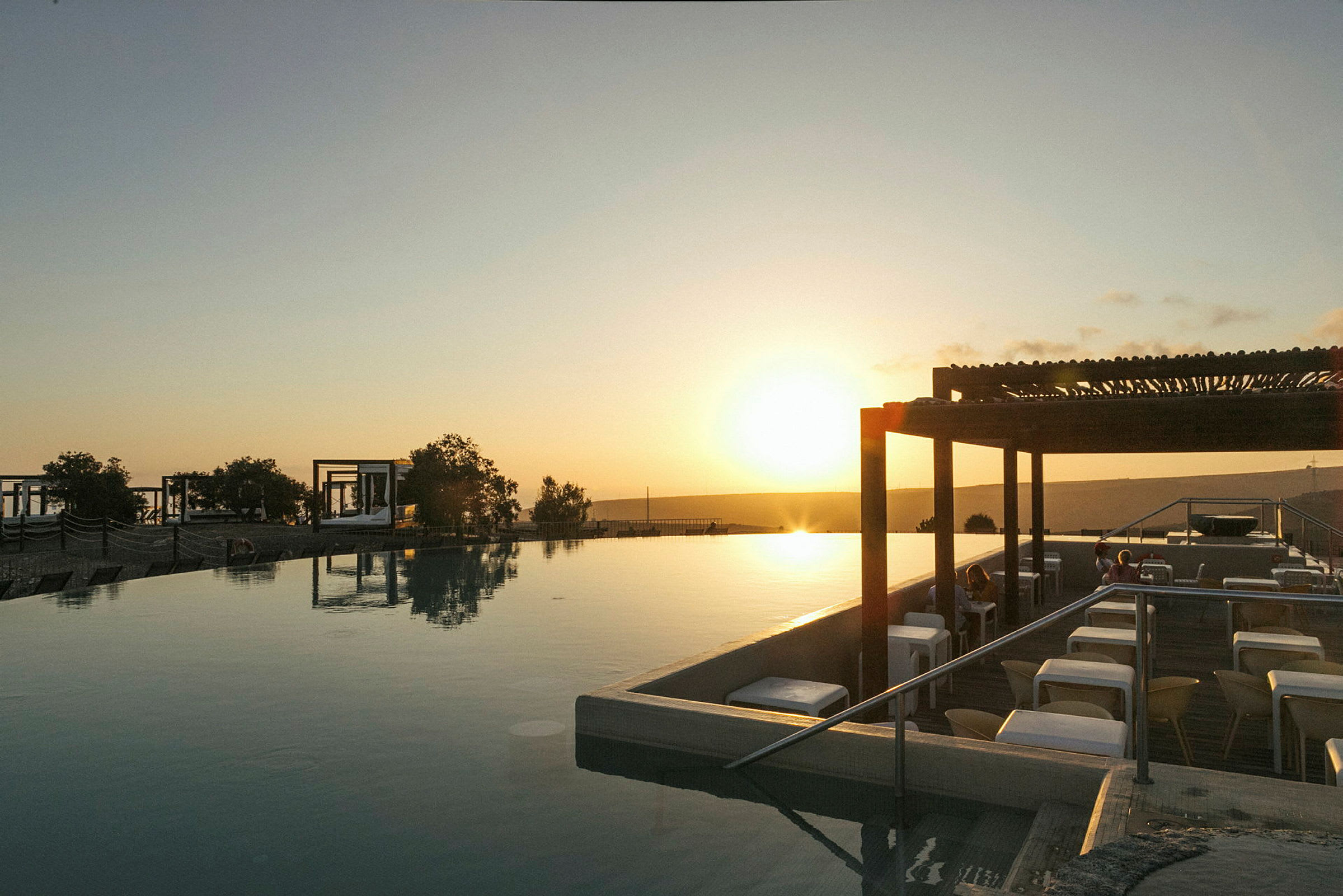 En solnedgång över en infinitypool med sittplatser vid sidan av. (AI-genererad text)