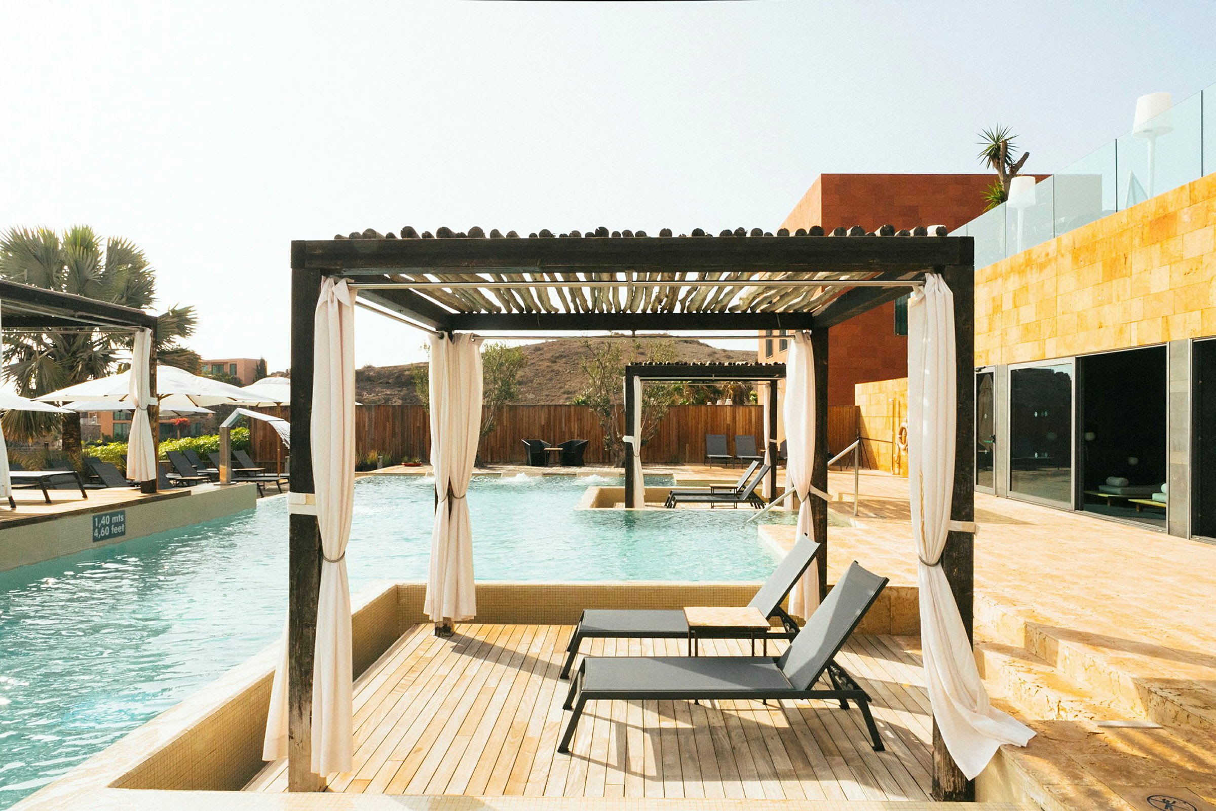 Poolområde med solsängar under en pergola. (AI-genererad text)
