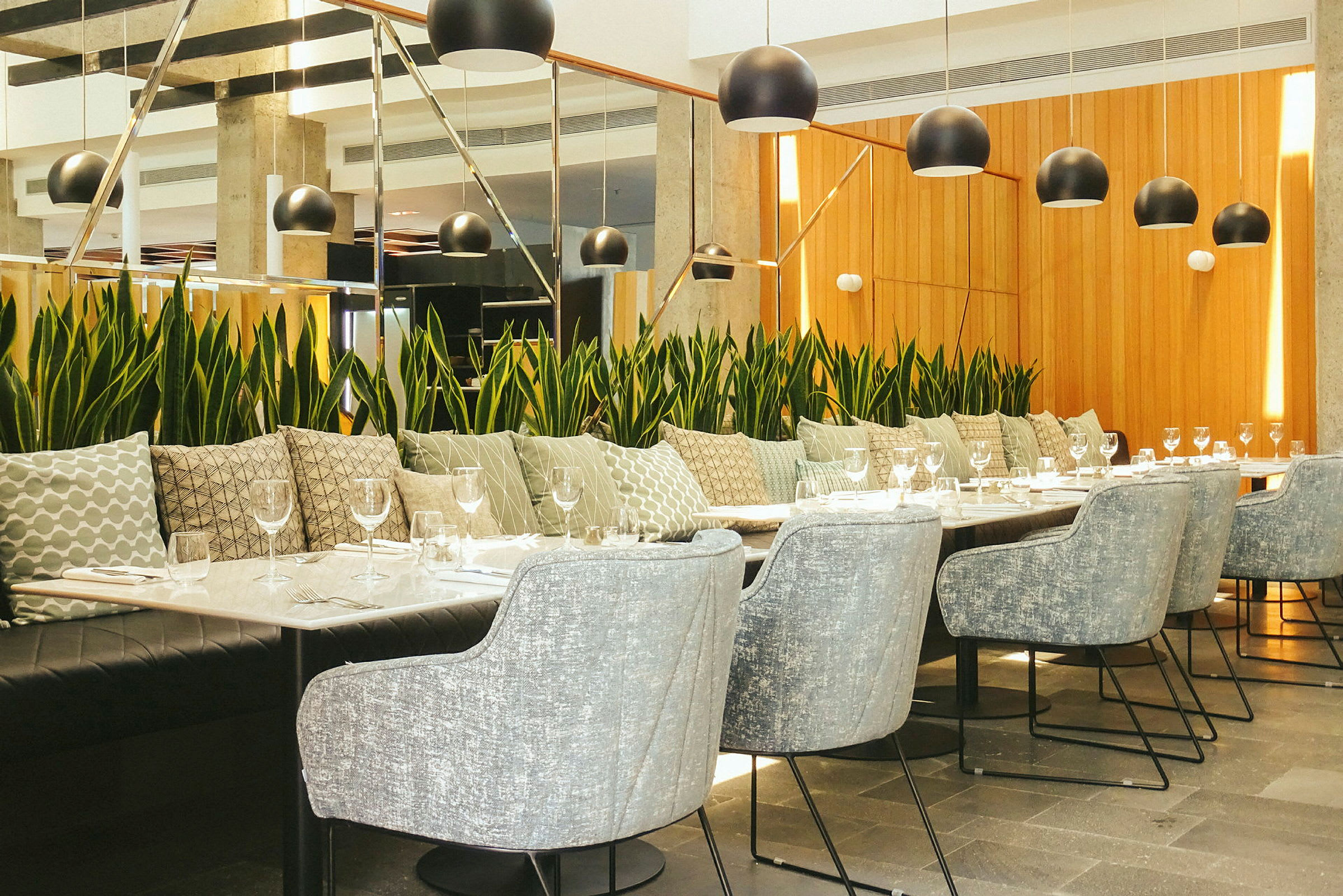 Modern restauranginredning med ett långbord omgiven av stolar och växtdekorationer. (AI-genererad text)