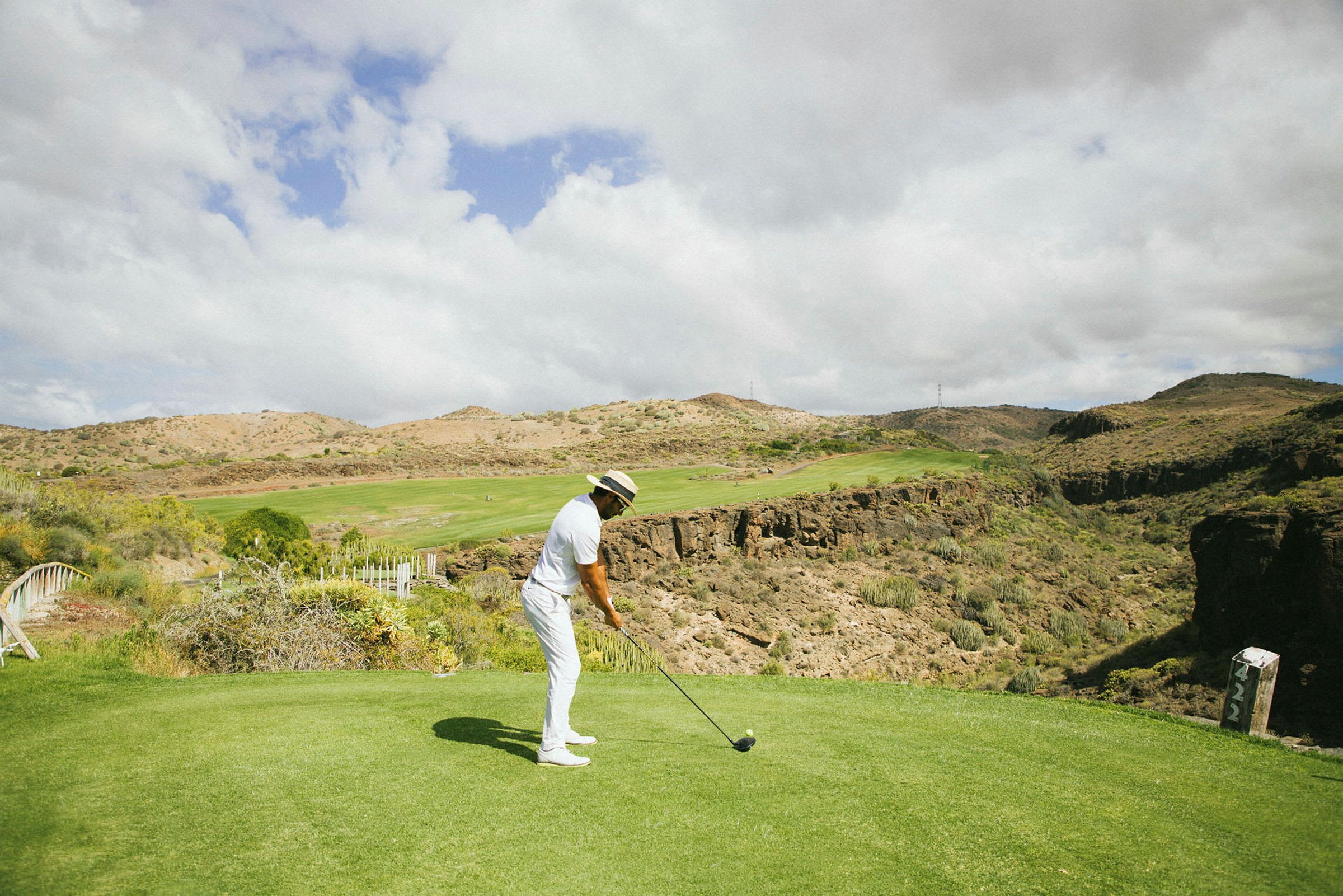 En person spelar golf på en bergig bana under en molnig himmel. (AI-genererad text)