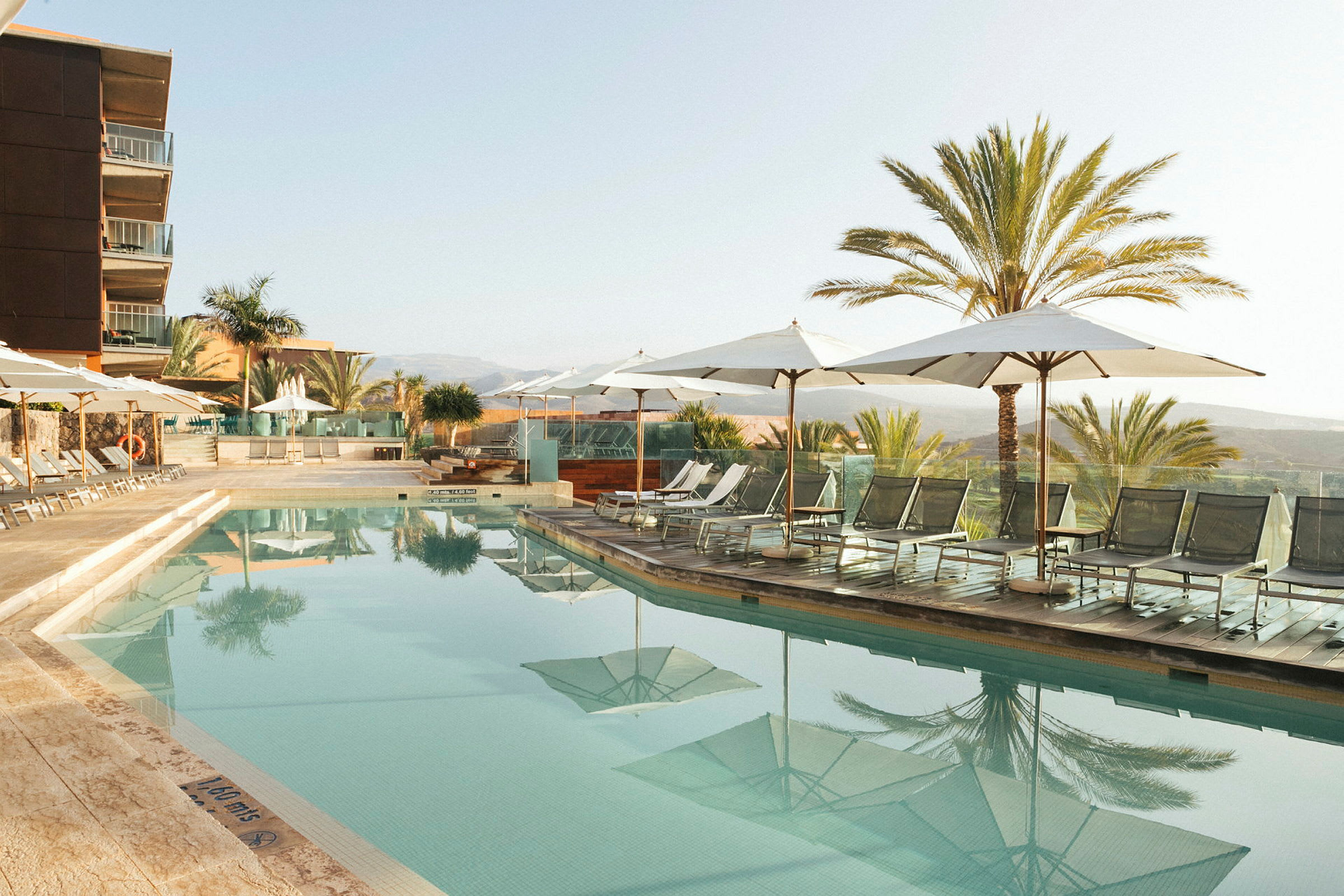 Utomhuspool vid hotell med solstolar och parasoller. (AI-genererad text)