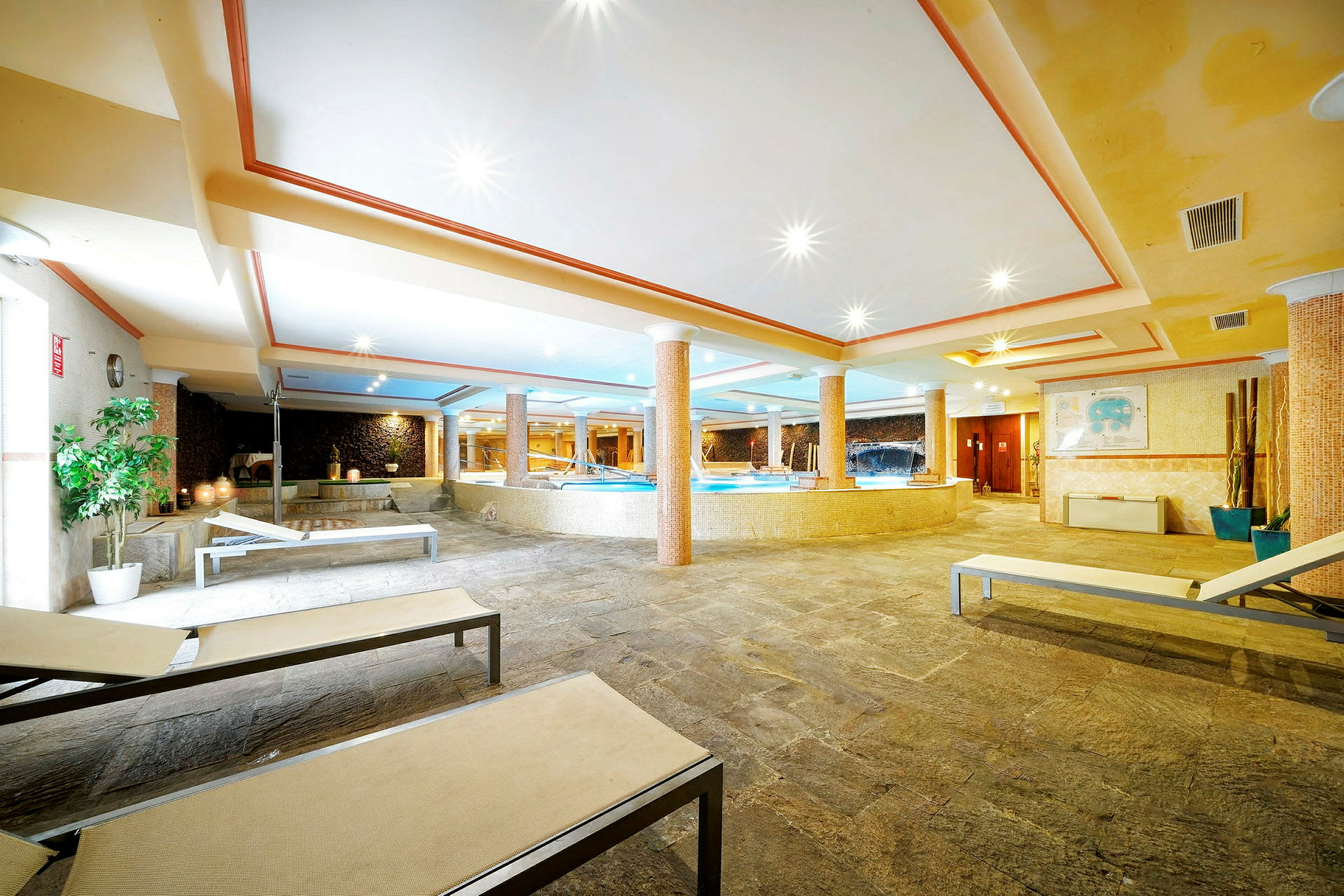 Bild av ett elegant spaområde inomhus med pool, solstolar och dekorativ belysning. (AI-genererad text)