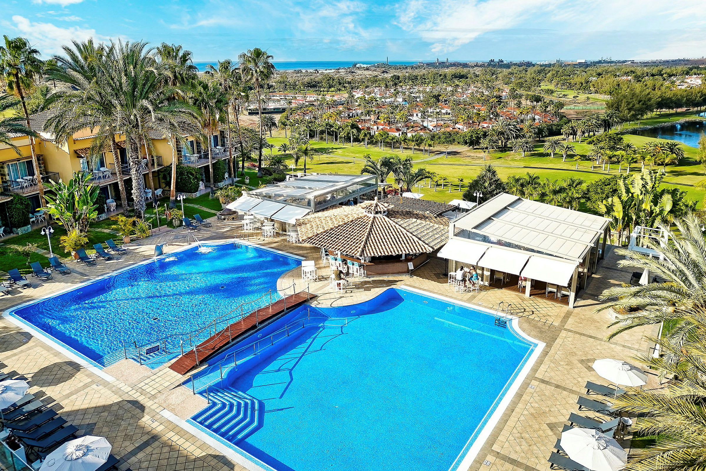 Bild av en hotellpool med solsängar, parasoller och omgivande byggnader. (AI-genererad text)
