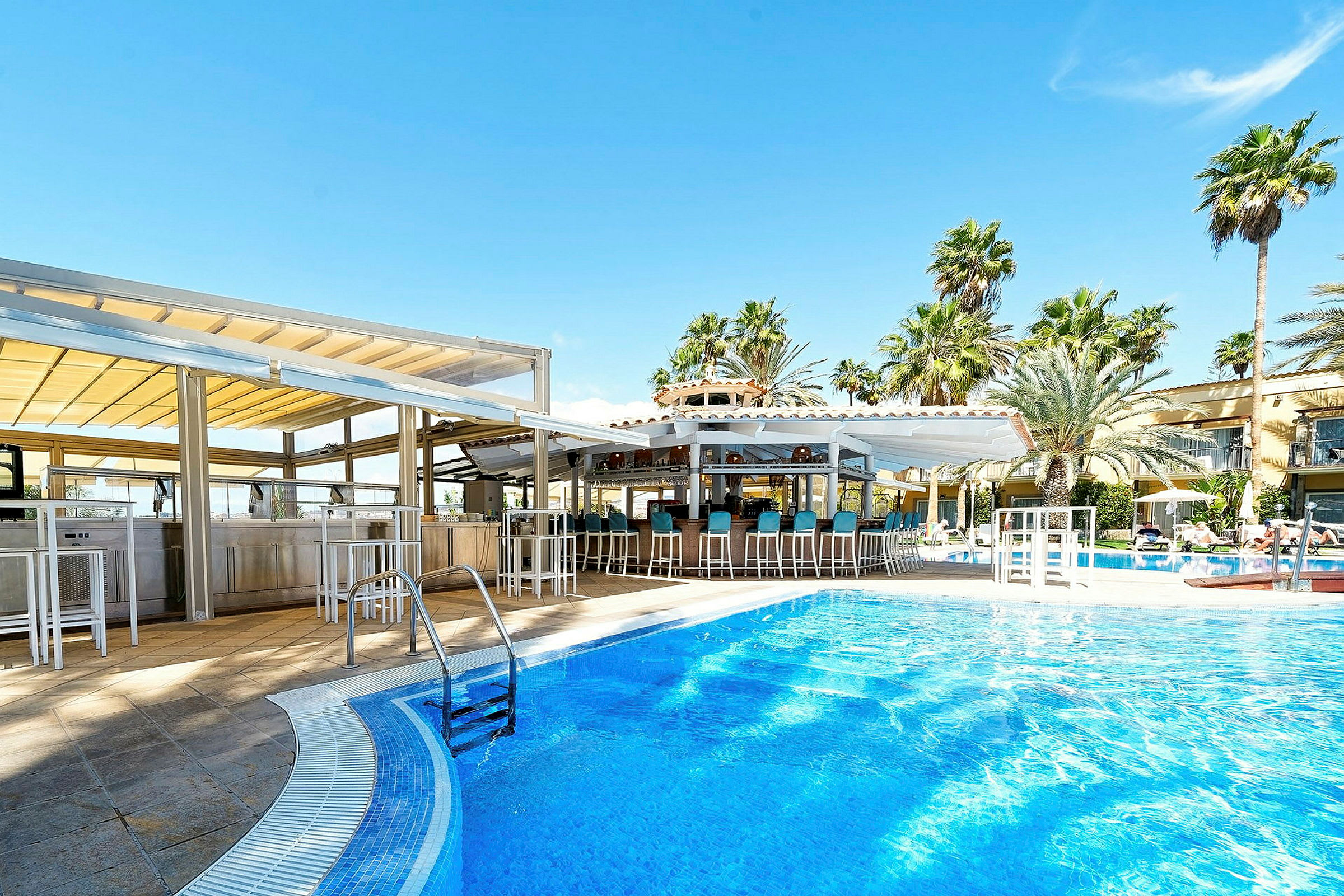 En utomhuspool med en poolbar omgiven av palmer och klarblå himmel. (AI-genererad text)