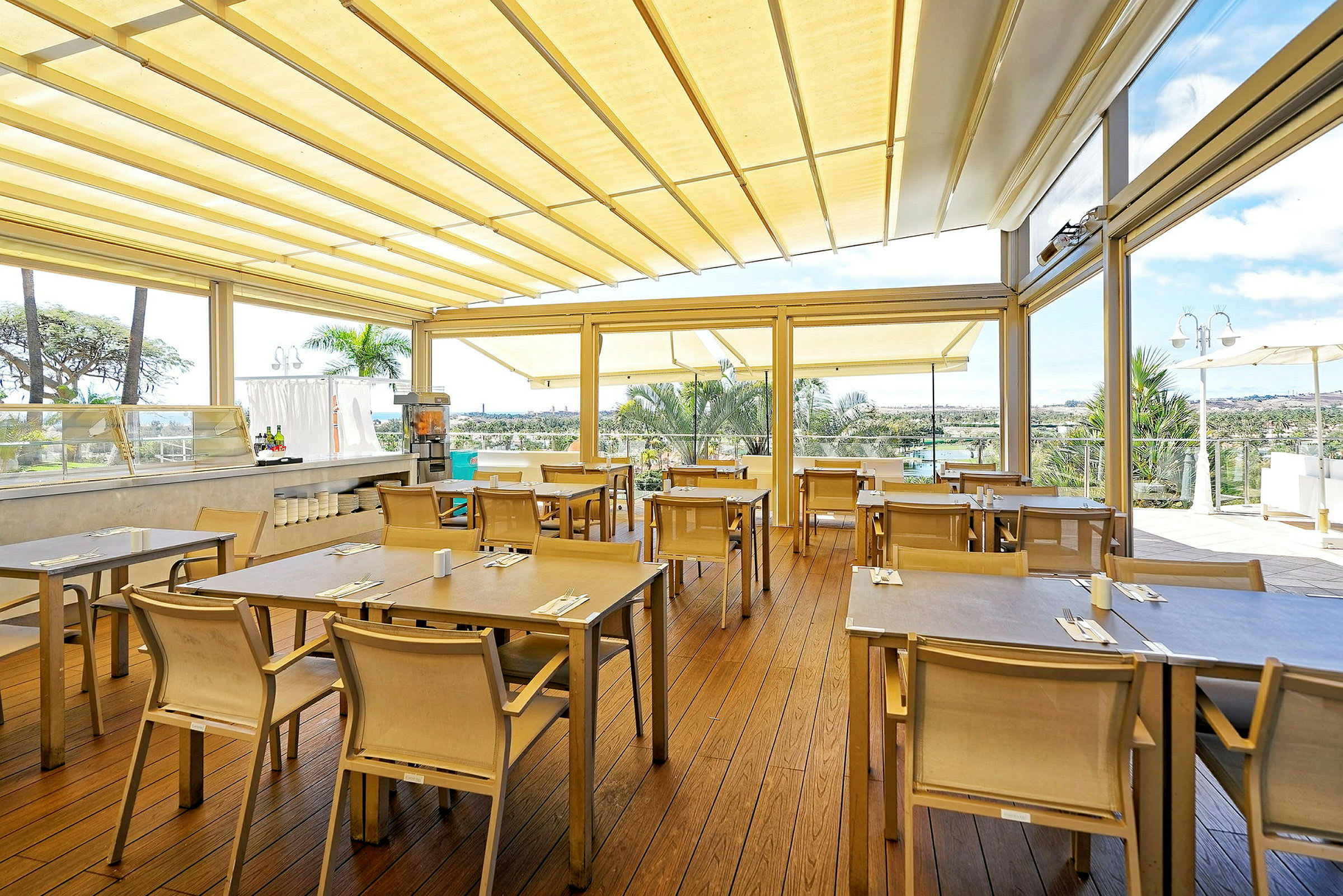 En utomhus restaurang med bord och stolar under ett tak. (AI-genererad text)