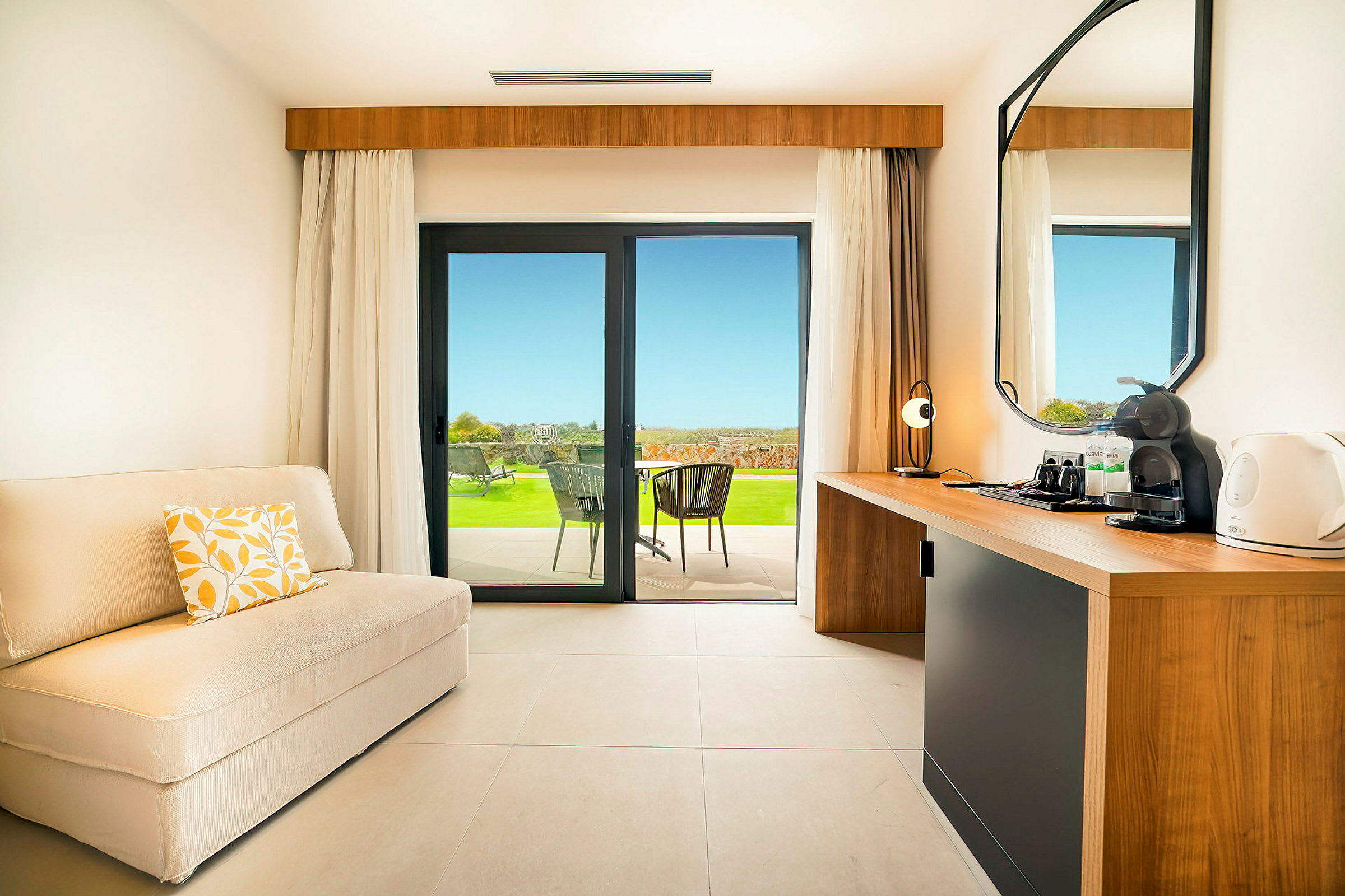 Ett hotellrum med bekväm sittplats och utsikt över en terrass med gräsmatta. (AI-genererad text)